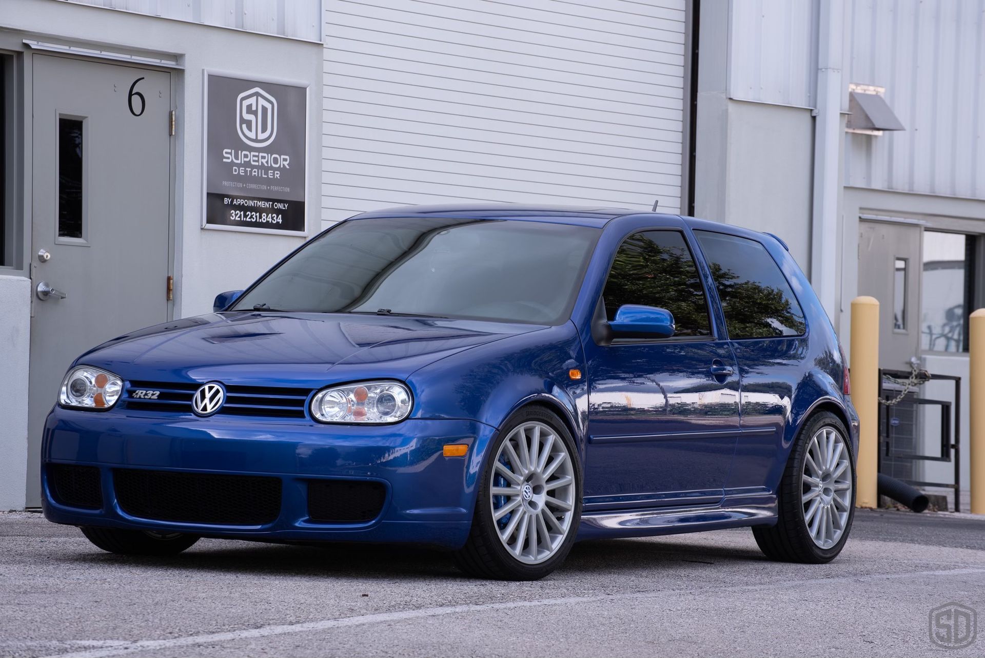 A blue volkswagen golf is parked in front of a building.