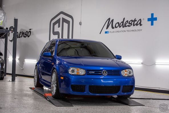 A blue car is parked on a lift in a garage.