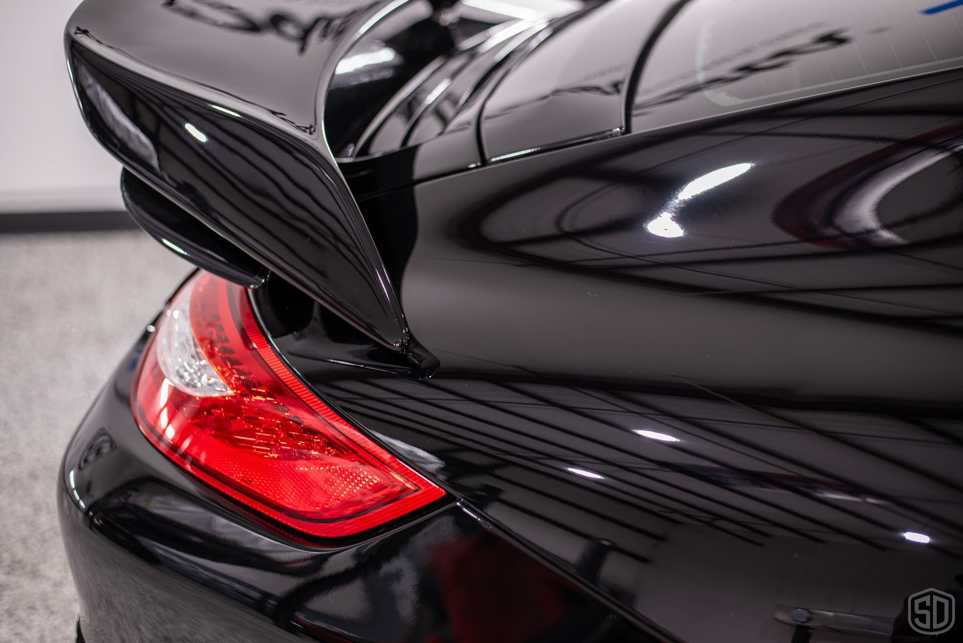 A closeup of a black car with renewed paint that is glossy, smooth, and free of imperfections.