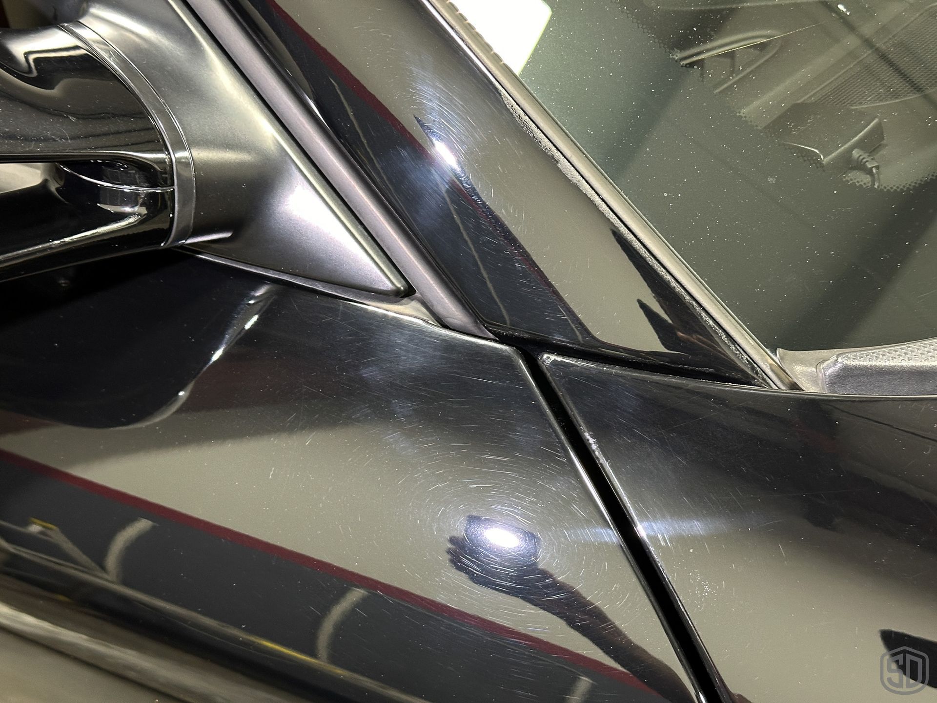 A close up of a car with scratches, swirls, and damage to the paint
