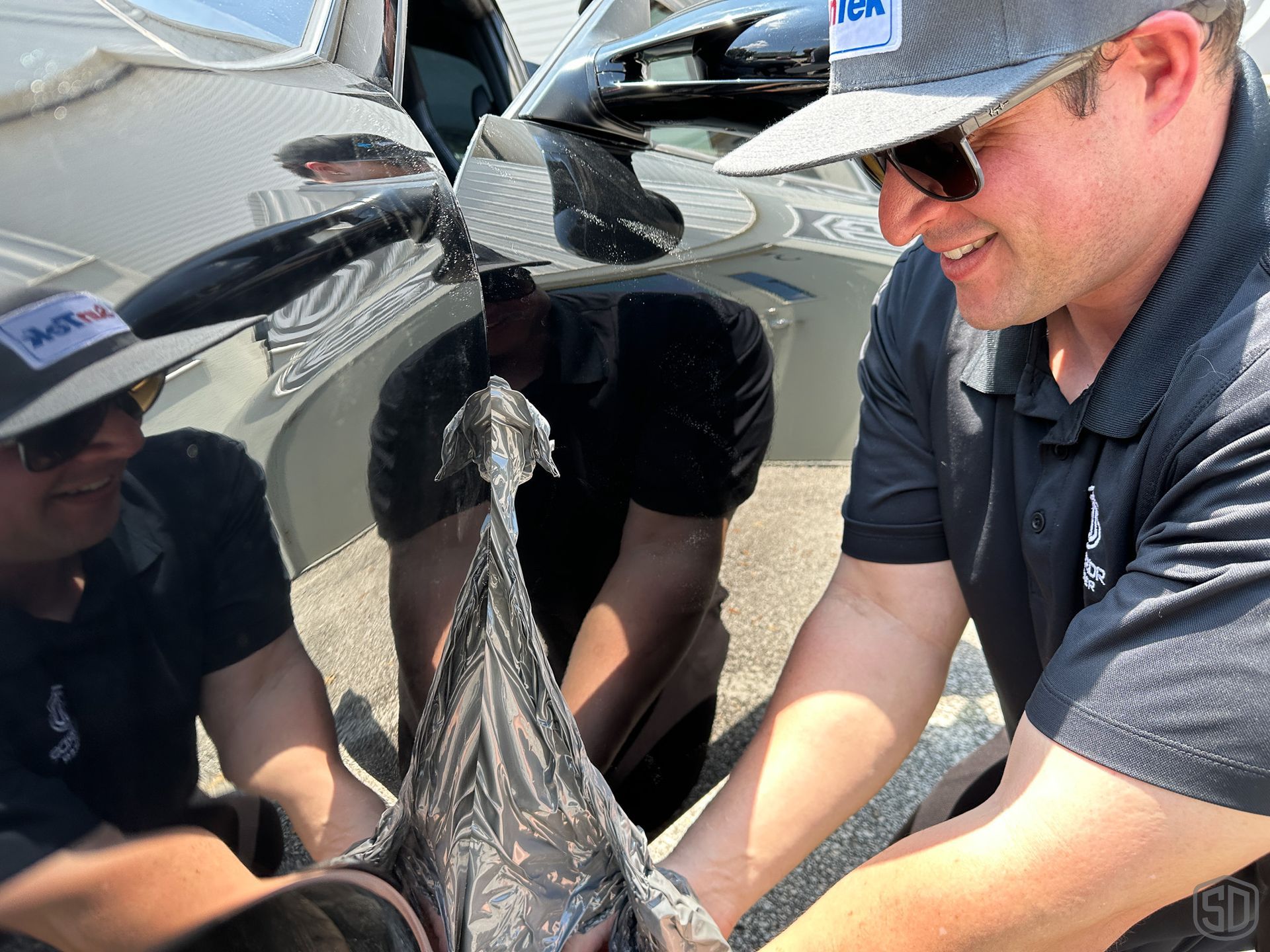 A man removing old vinyl wrap from black Porsche 911 Turbo