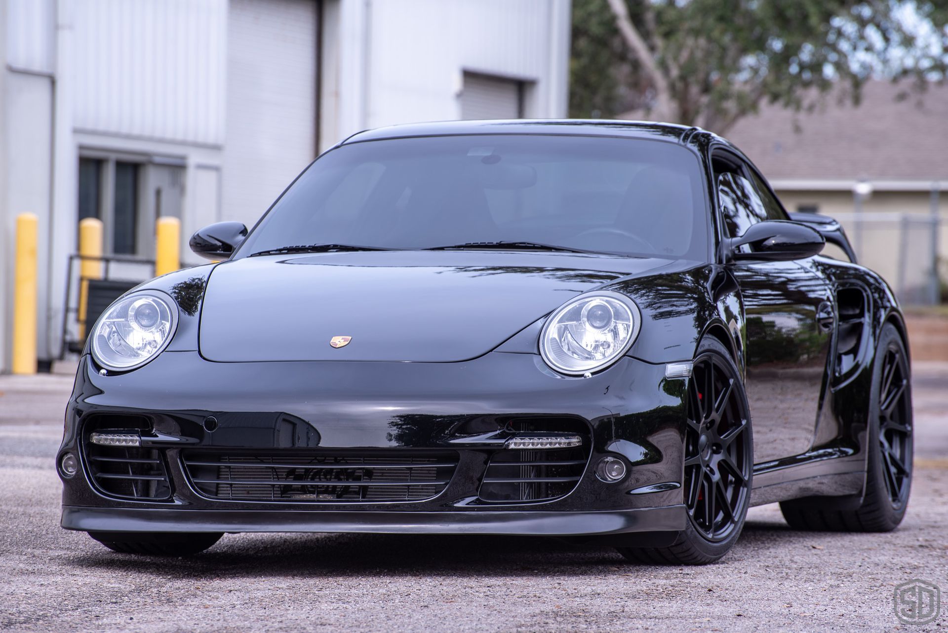 A black porsche 911 turbo is parked in front of a building.