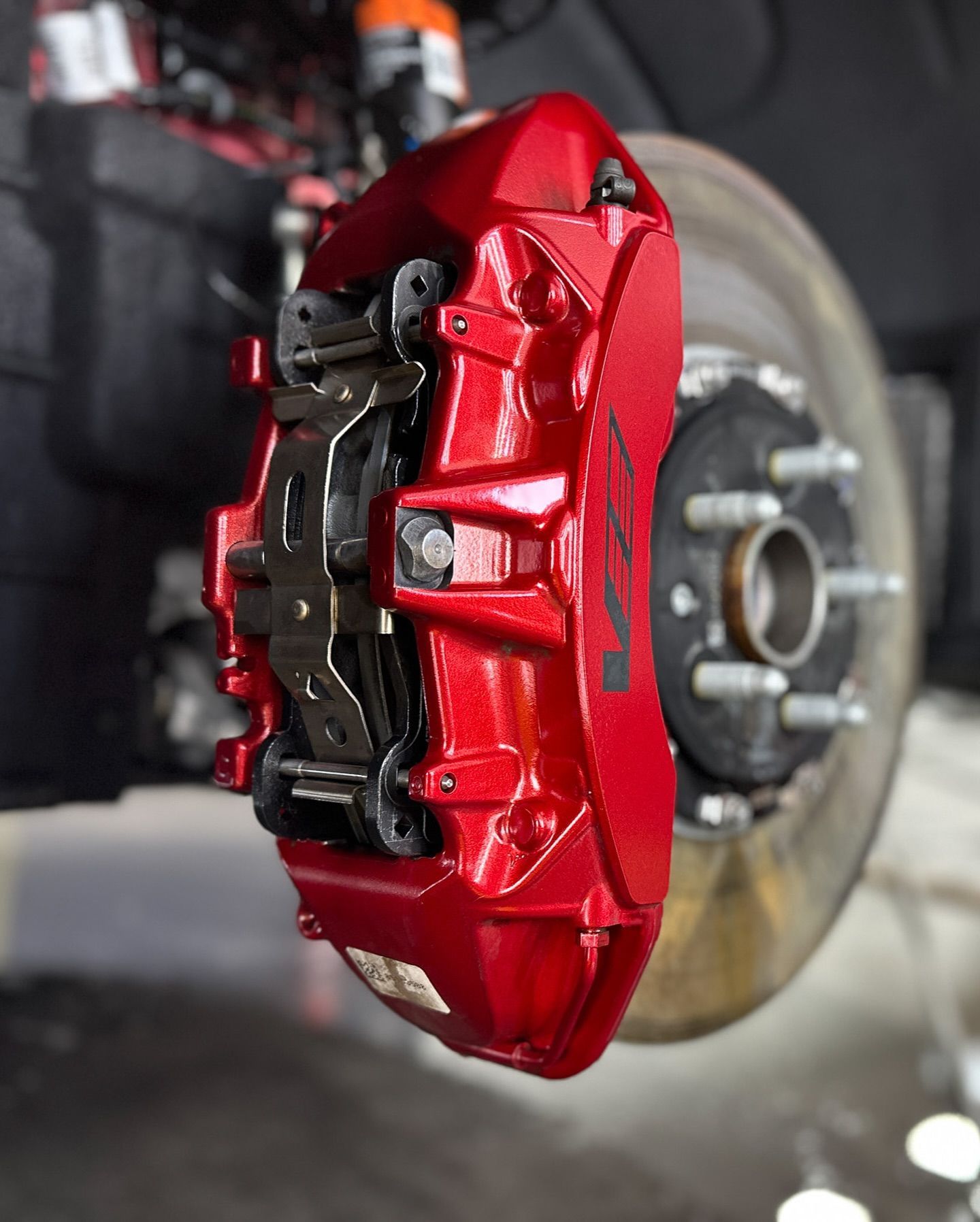 A close up of a red brake caliper on a car