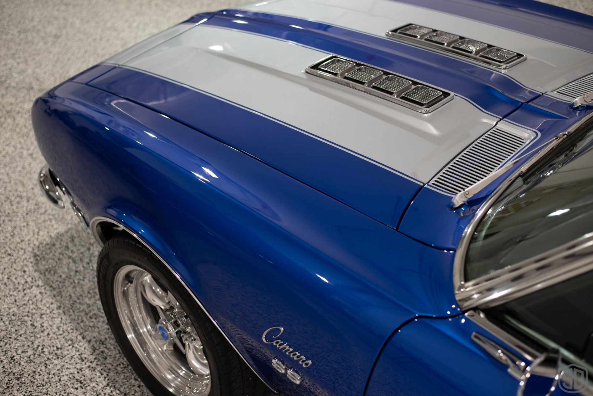 A blue and white chevrolet camaro is parked in a garage.