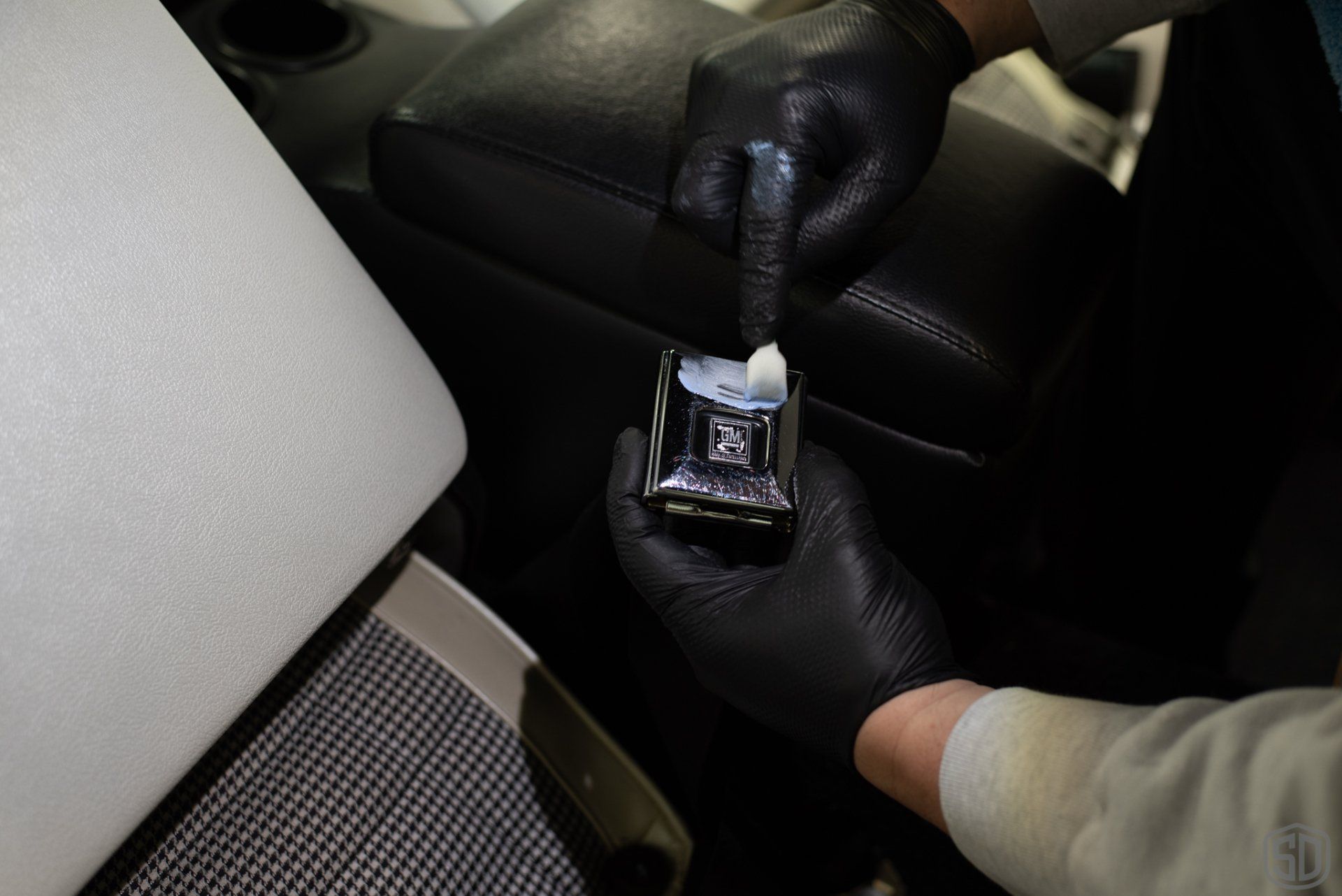 A person wearing black gloves is holding a small object in their hand.