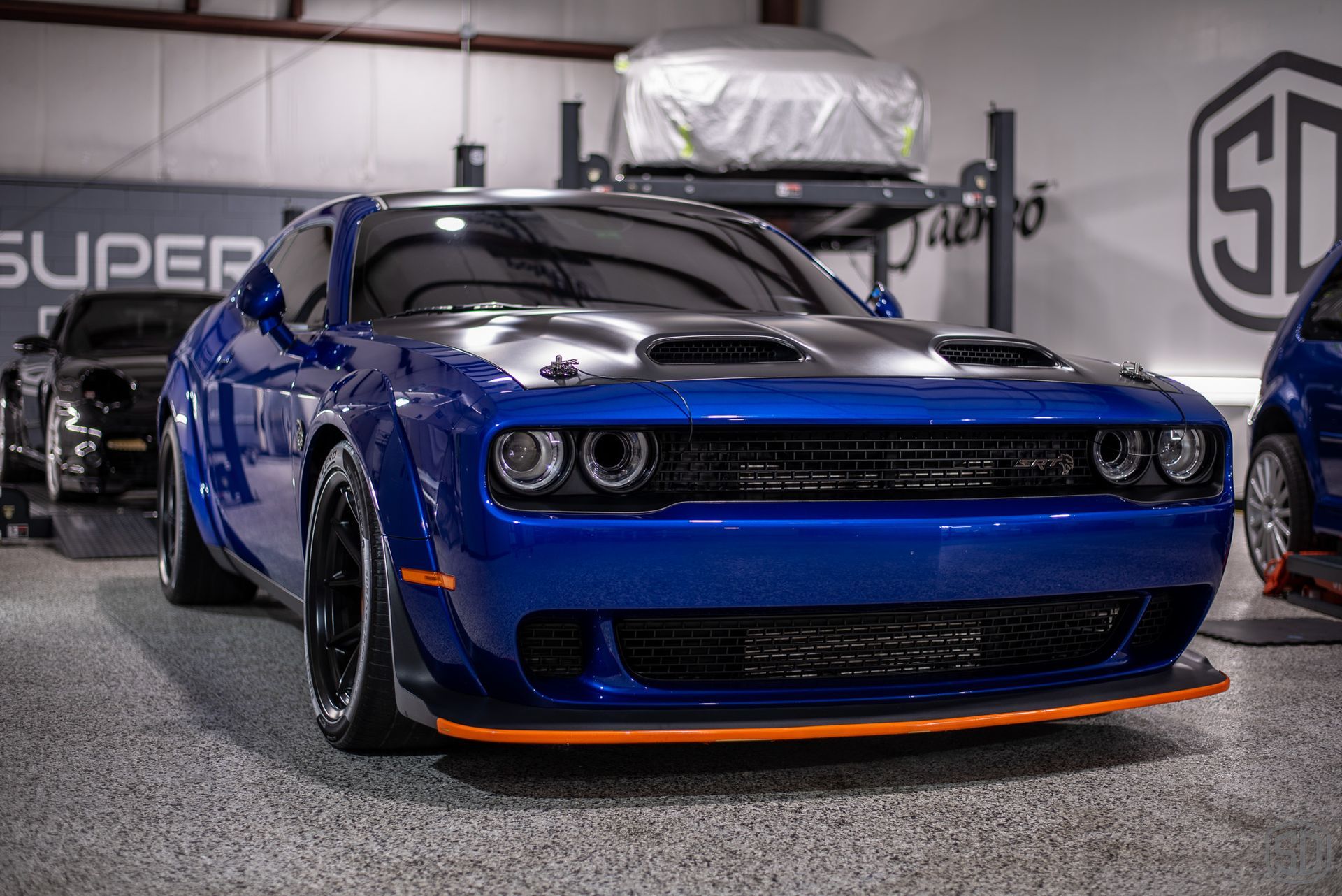 A blue dodge challenger is parked in a garage.