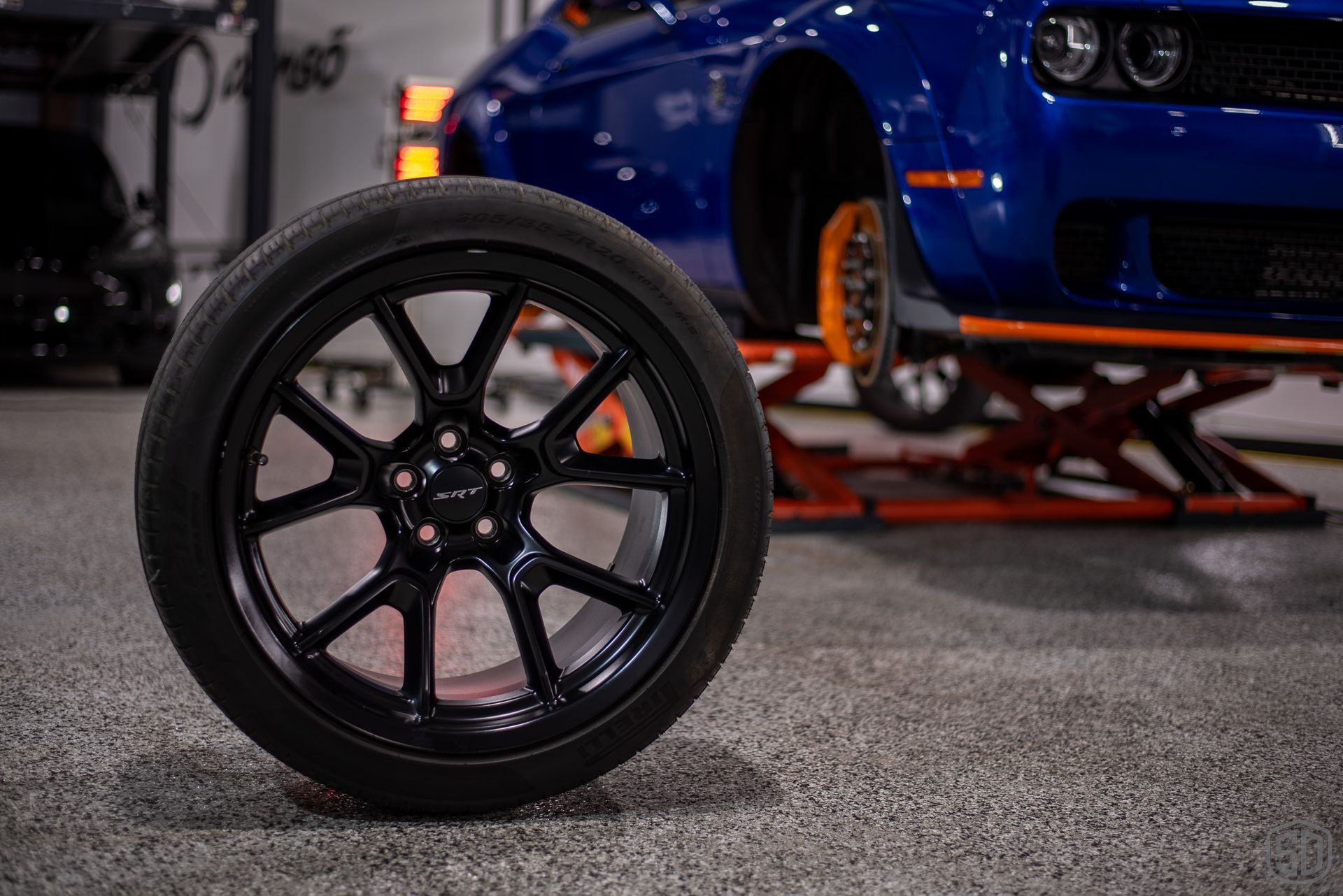 A close up of a tire on a car wheel in a garage.