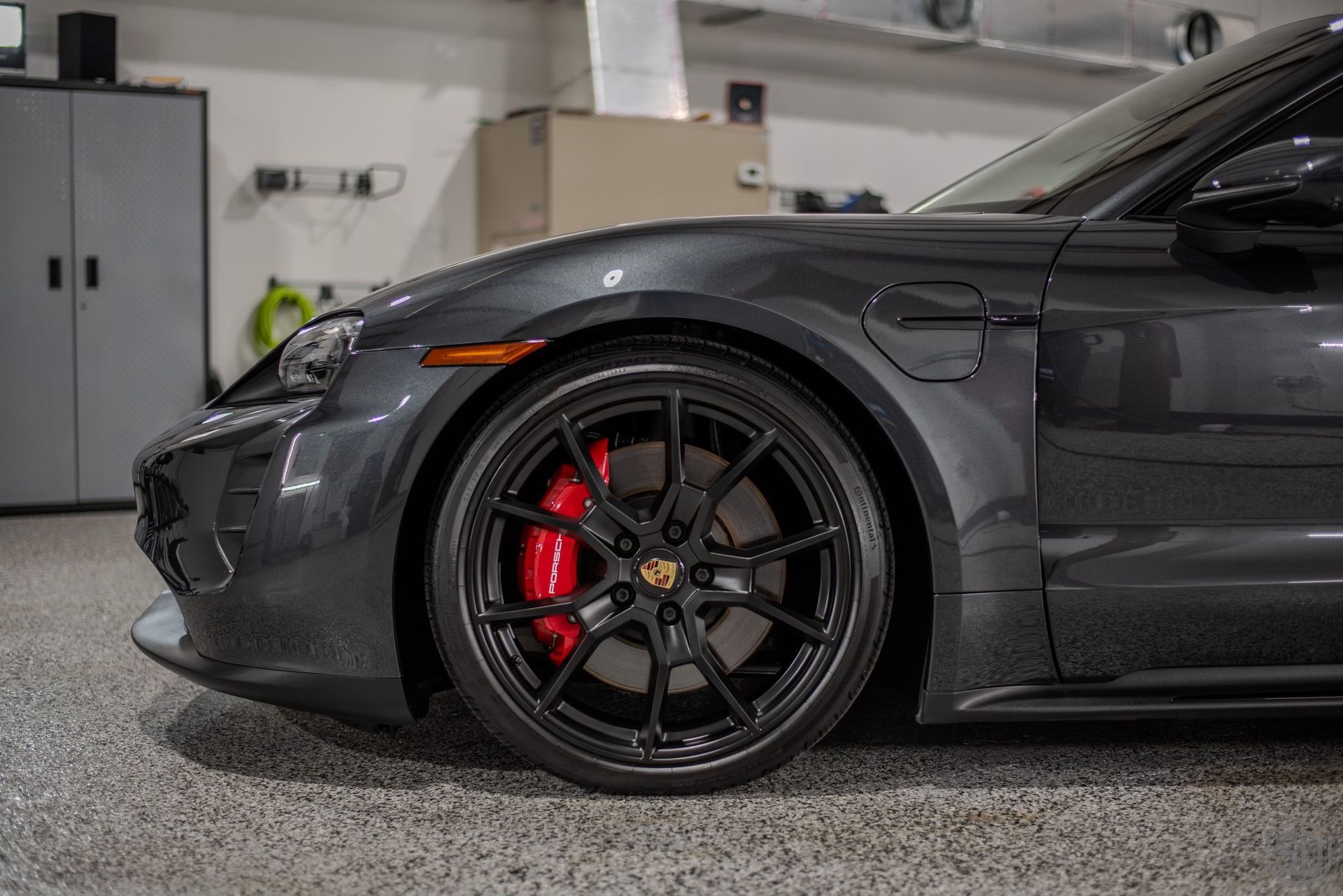 A black porsche taycan is parked in a garage.