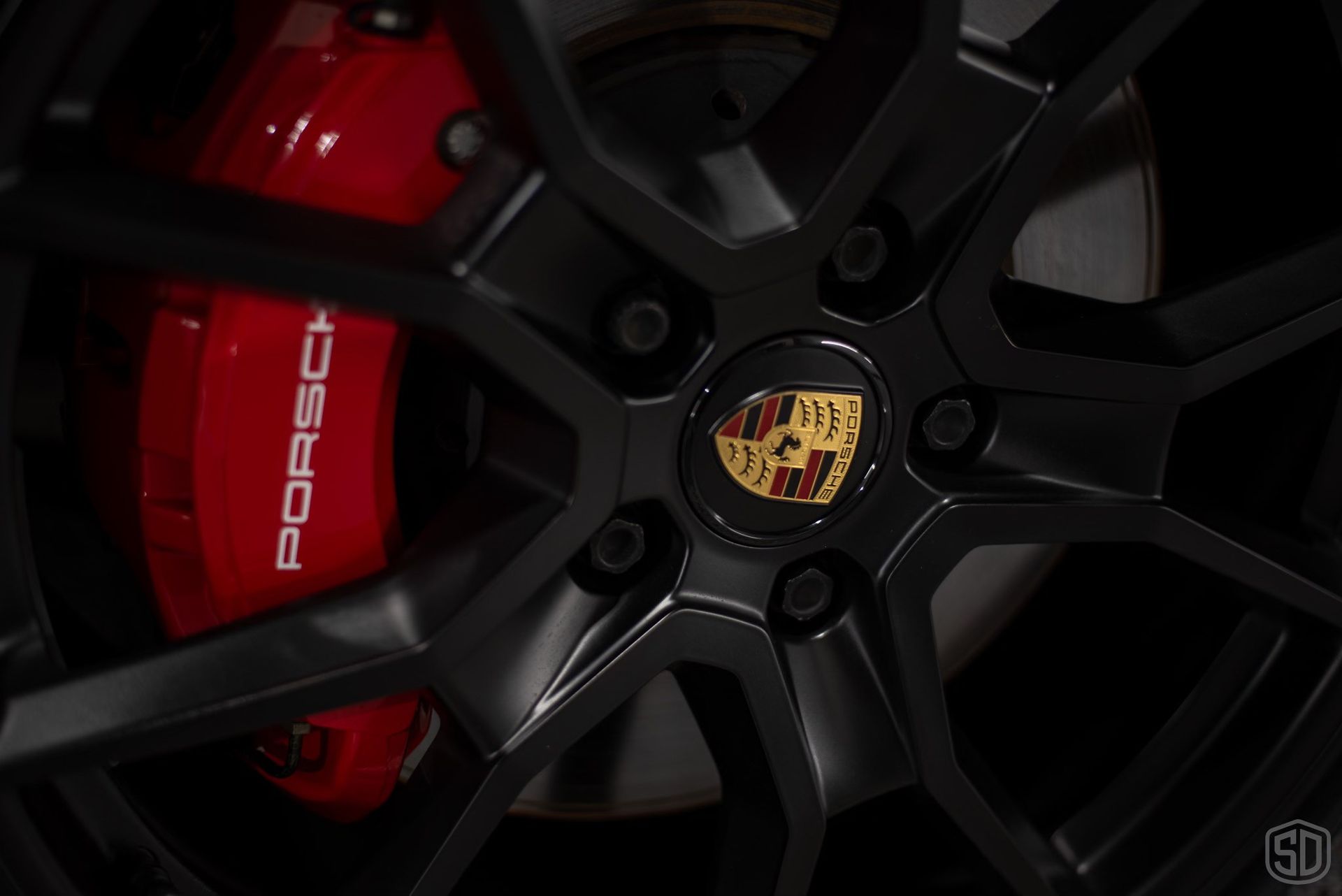 A close up of a porsche wheel with red brake calipers.