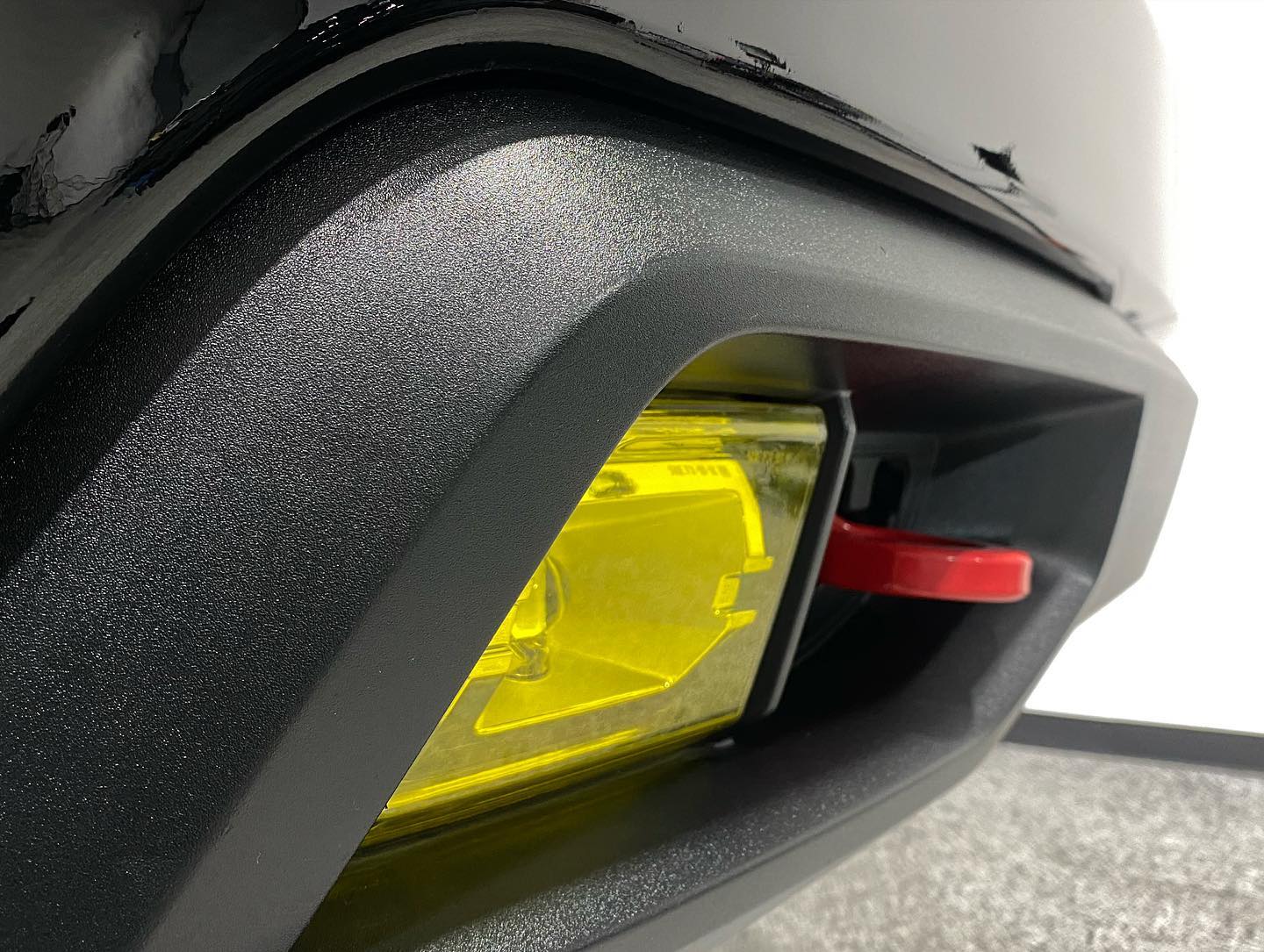 A close up of a car 's bumper with a yellow light on it.