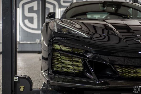 A black sports car is parked on a lift in a garage.