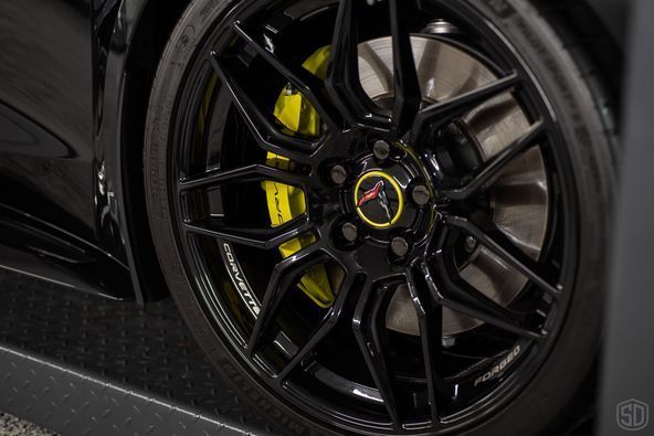 A close up of a black car wheel with yellow brake calipers.