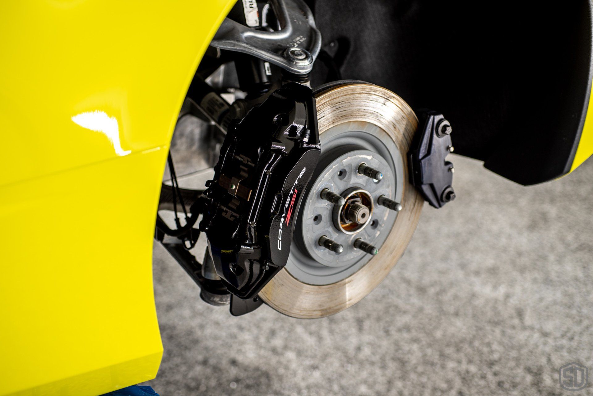 A close up of a yellow car with a black brake caliper.