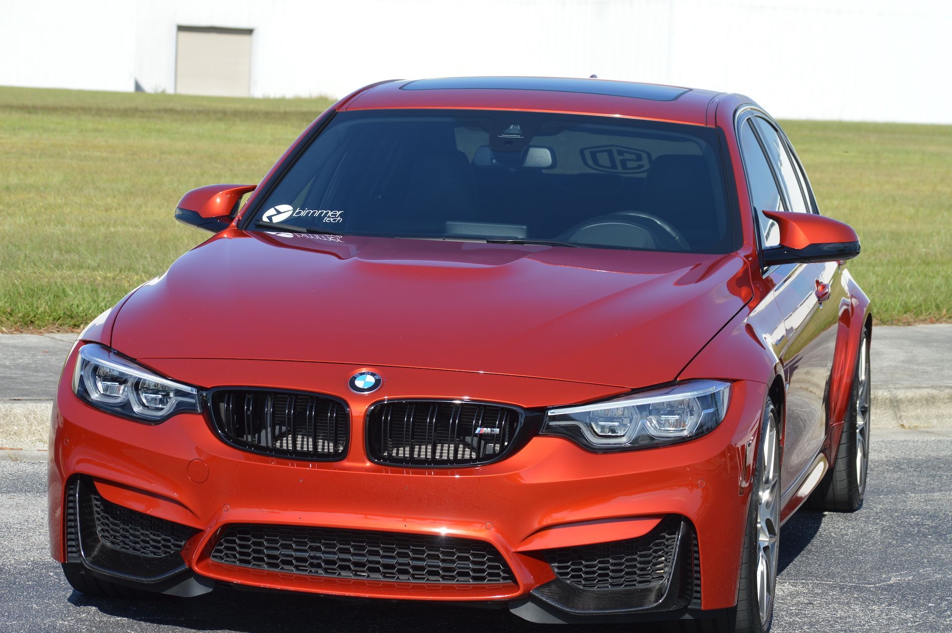 A red bmw m3 is parked on the side of the road.