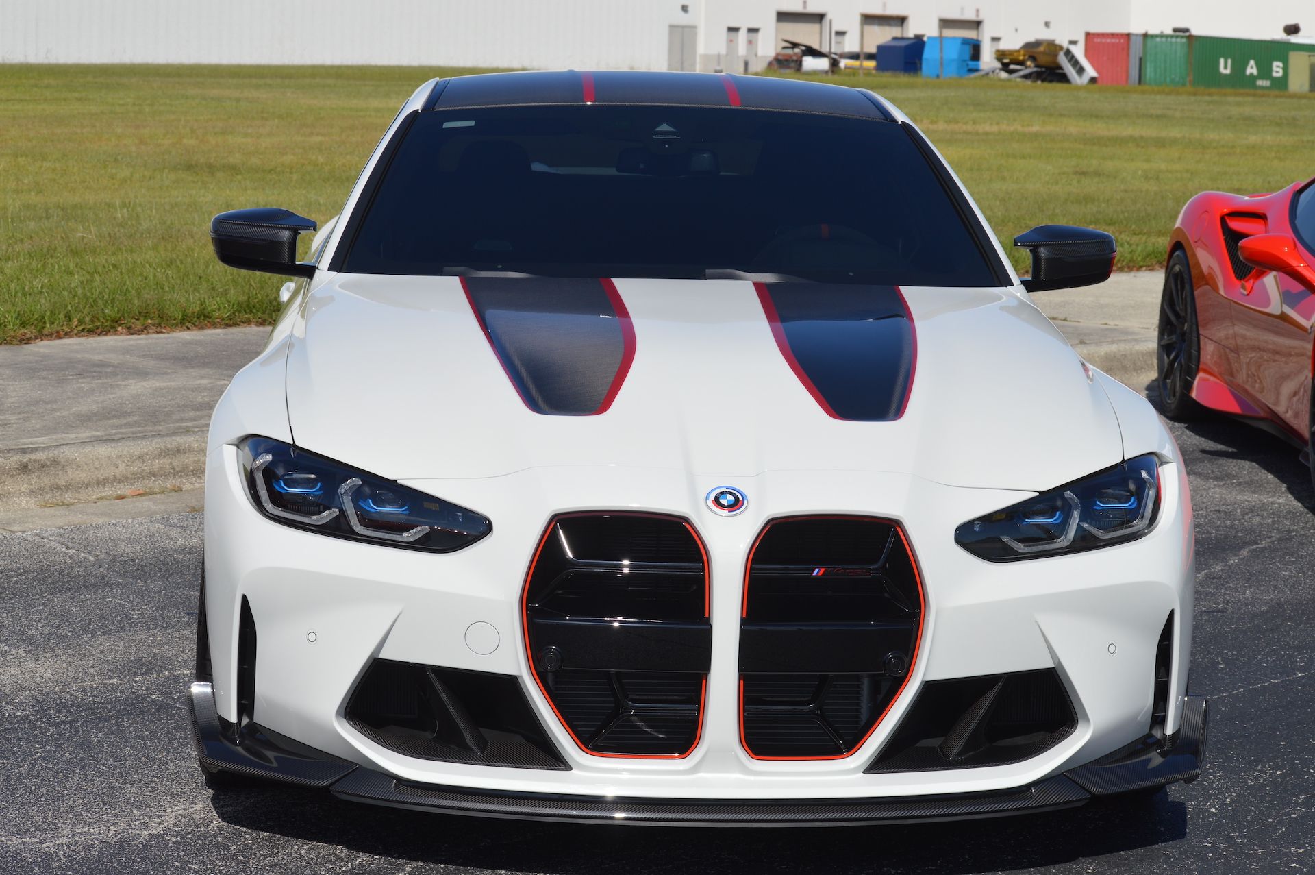 A white bmw with red and black stripes on the hood