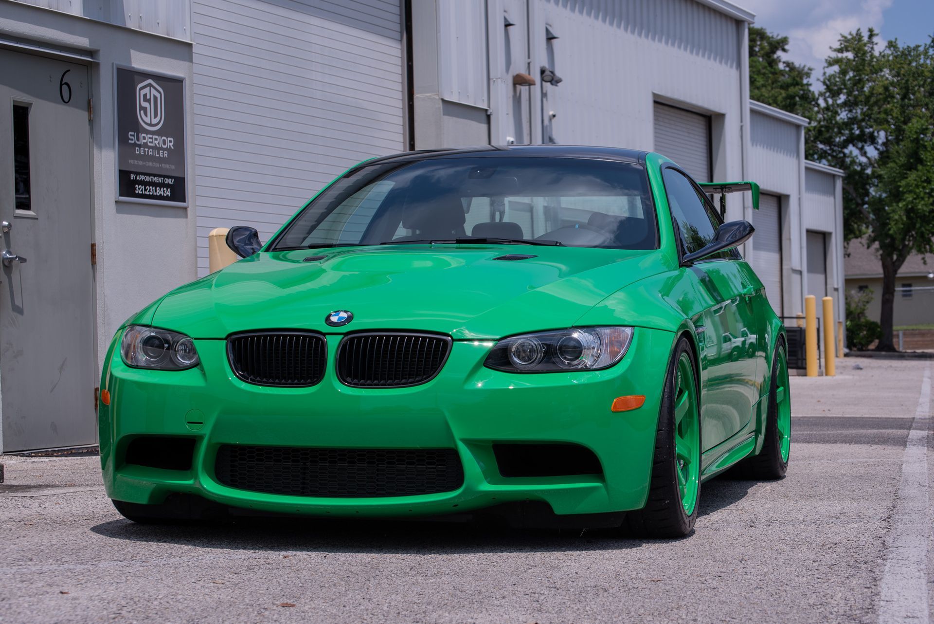 A green bmw is parked in front of a building
