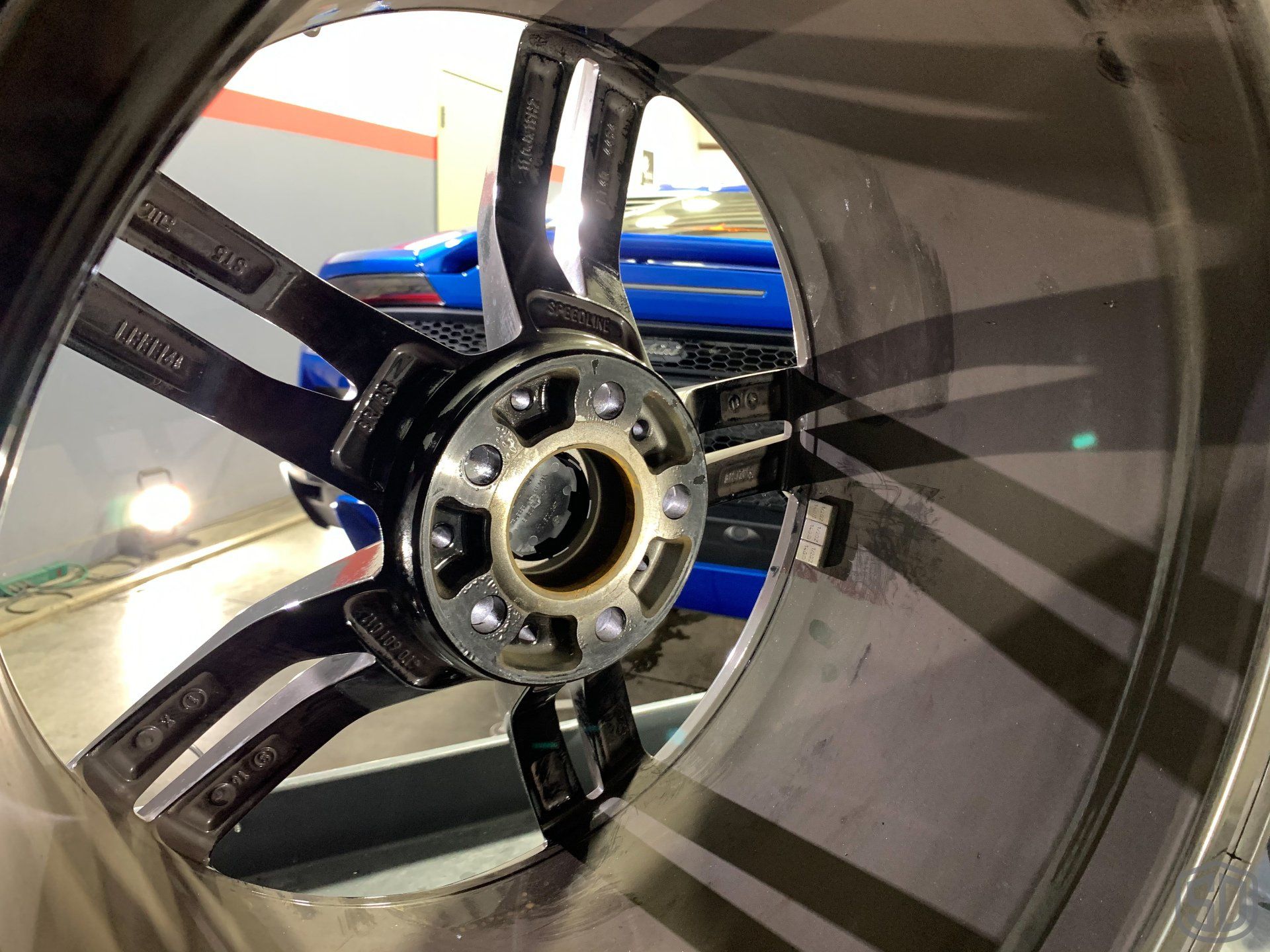 A close up of a car wheel with a blue car in the background