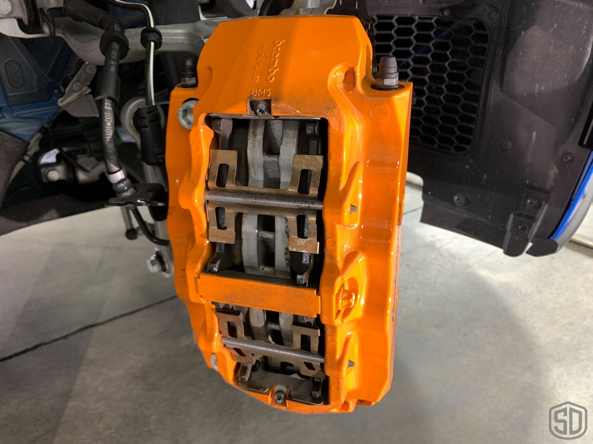 A close up of an orange brake caliper on a car