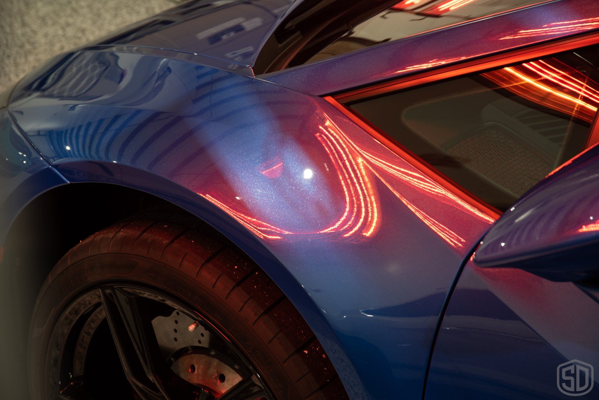 A close up of a blue sports car with red lights on the side.