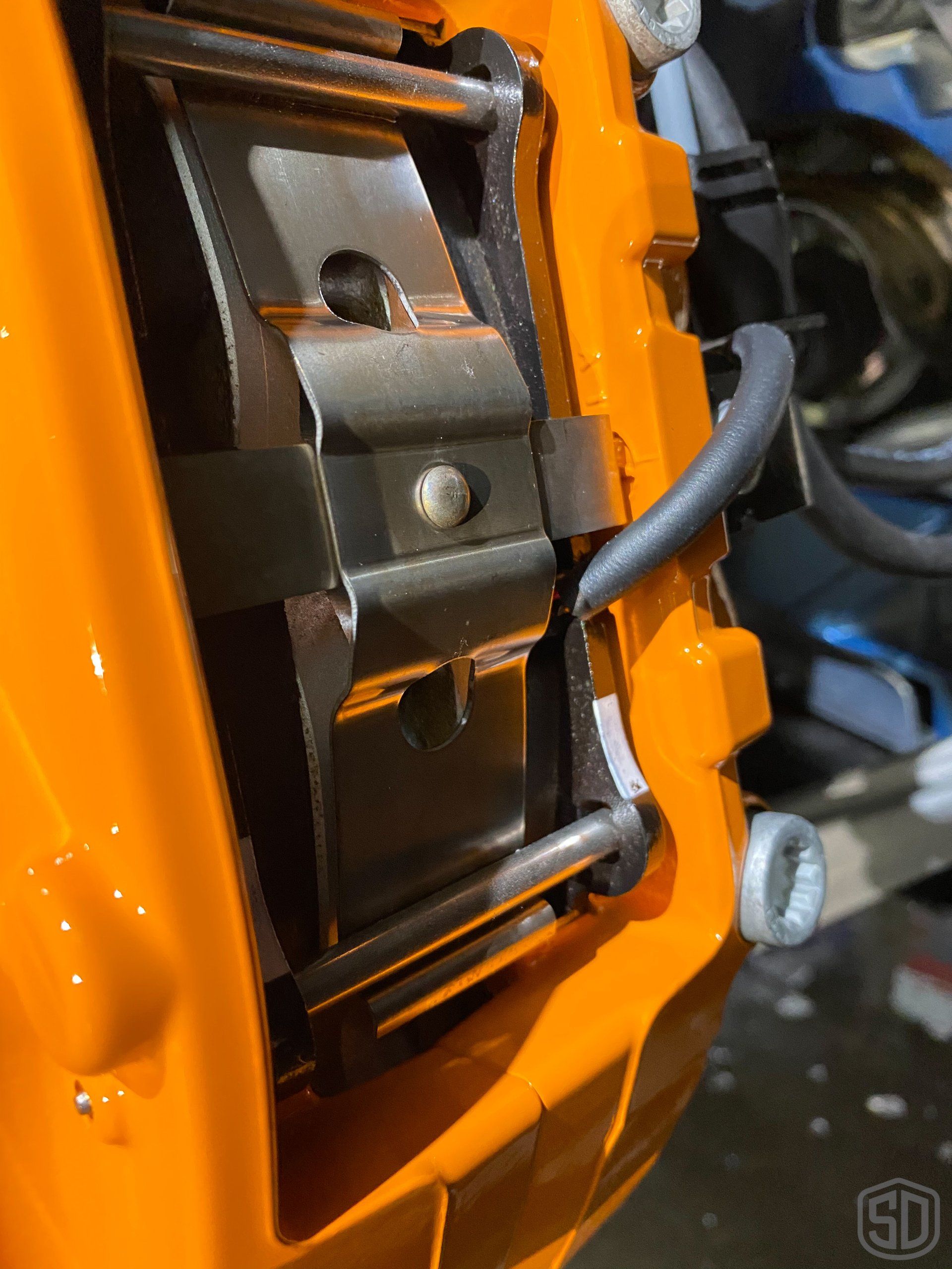 A close up of a brake caliper on an orange car