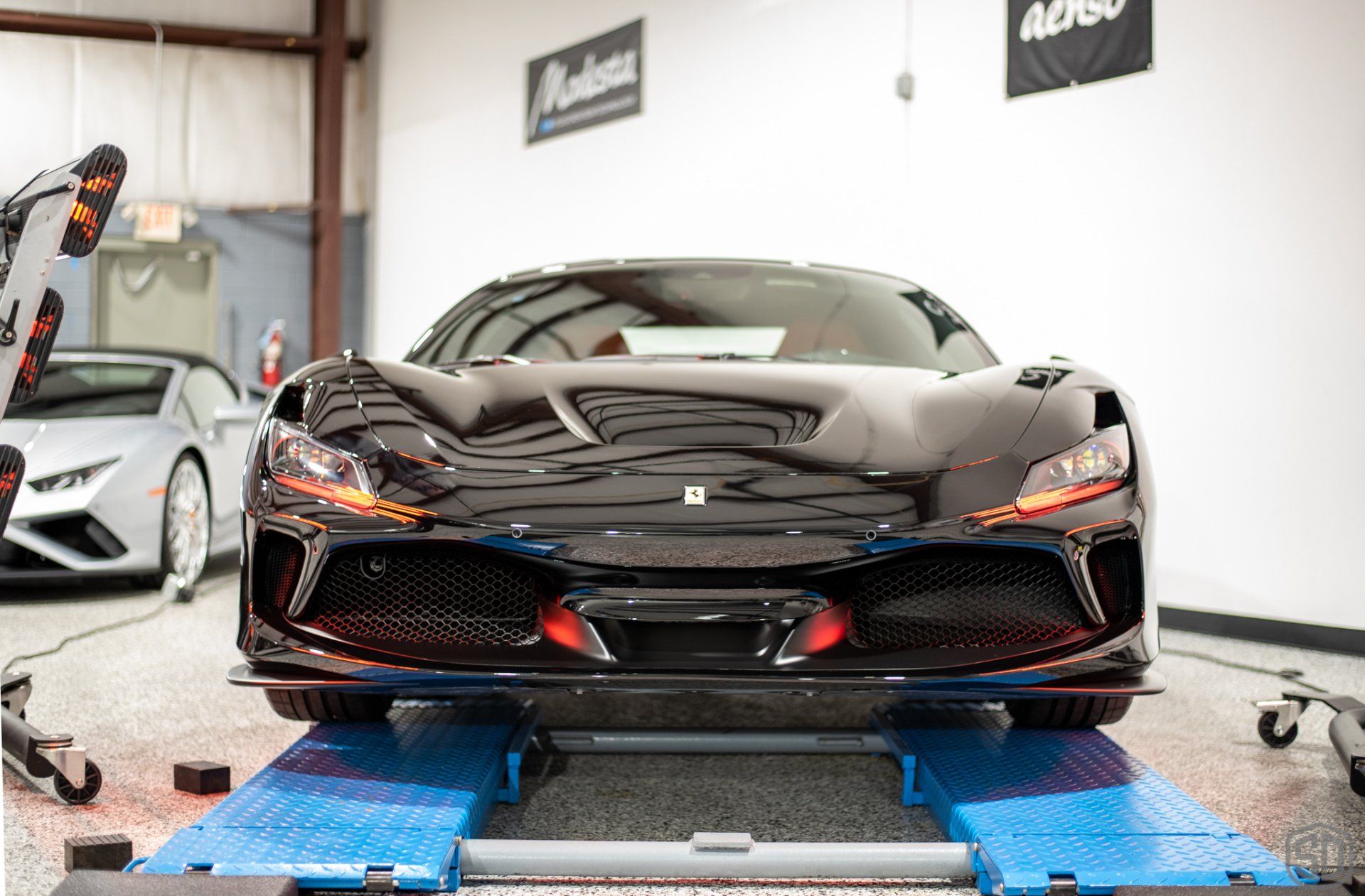A black sports car is sitting on top of a blue ramp in a garage.