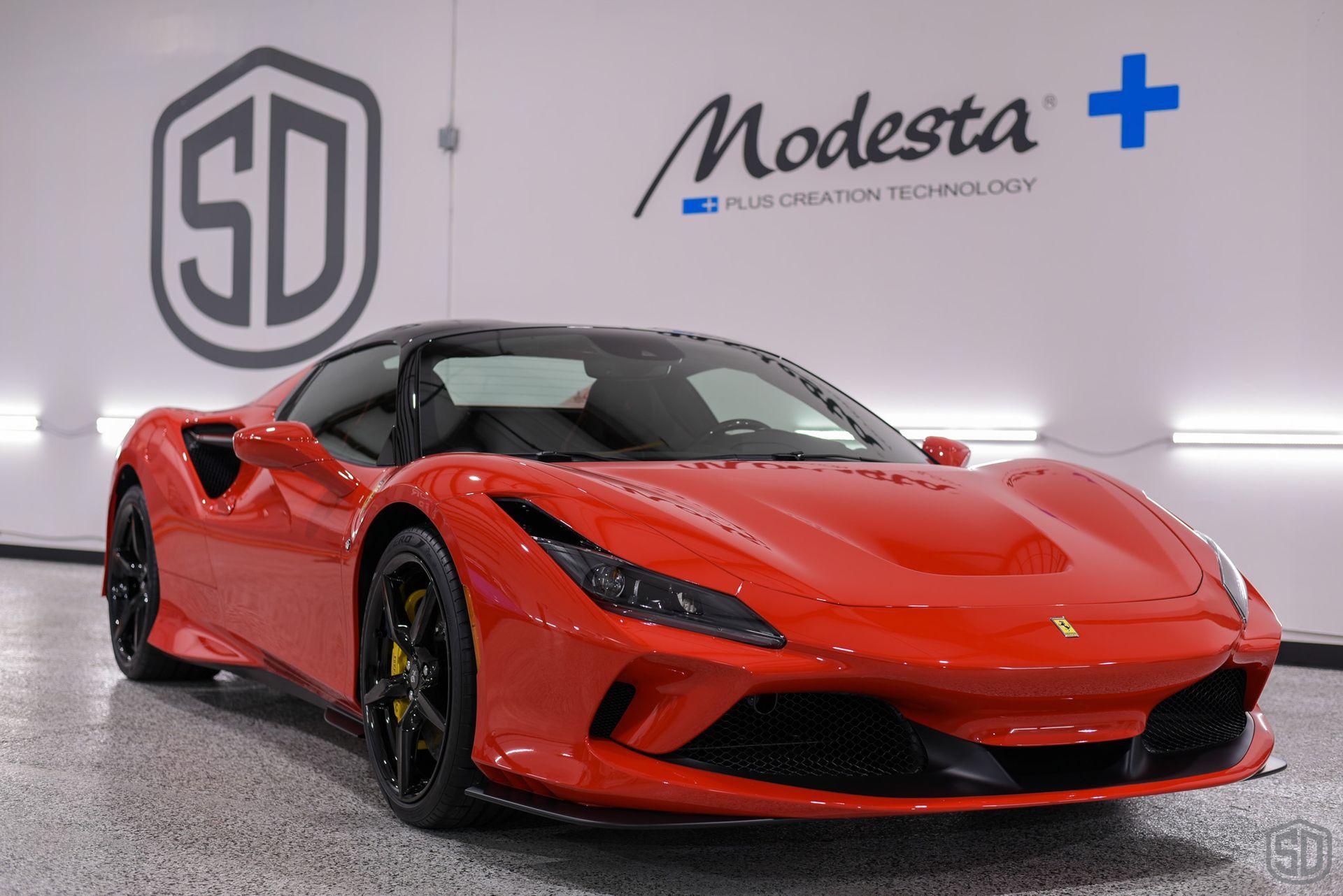 A red ferrari f8 spider is parked in front of a sd logo.