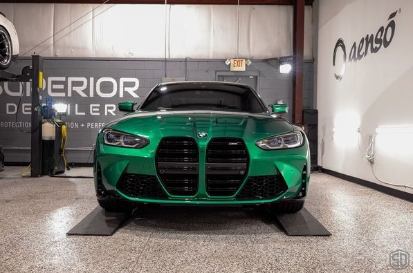 A green bmw m3 is parked in a garage.