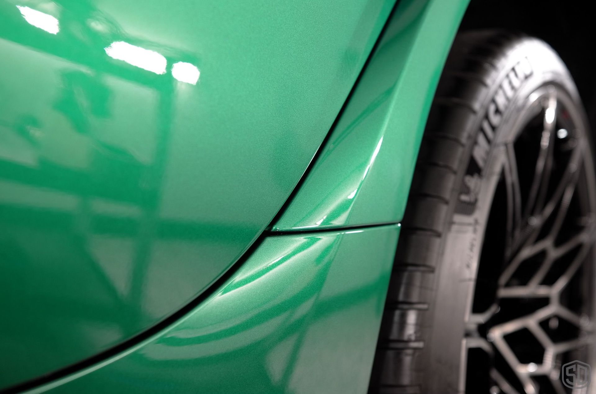 A close up of a green car with a tire on it.