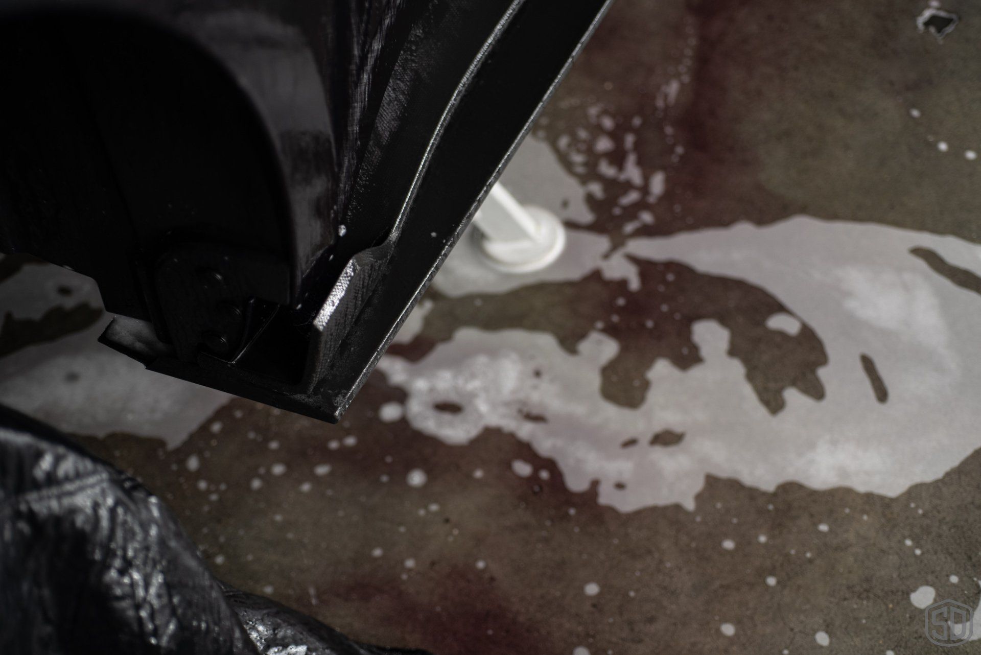 A black and white photo of a person spraying soap on a concrete floor.