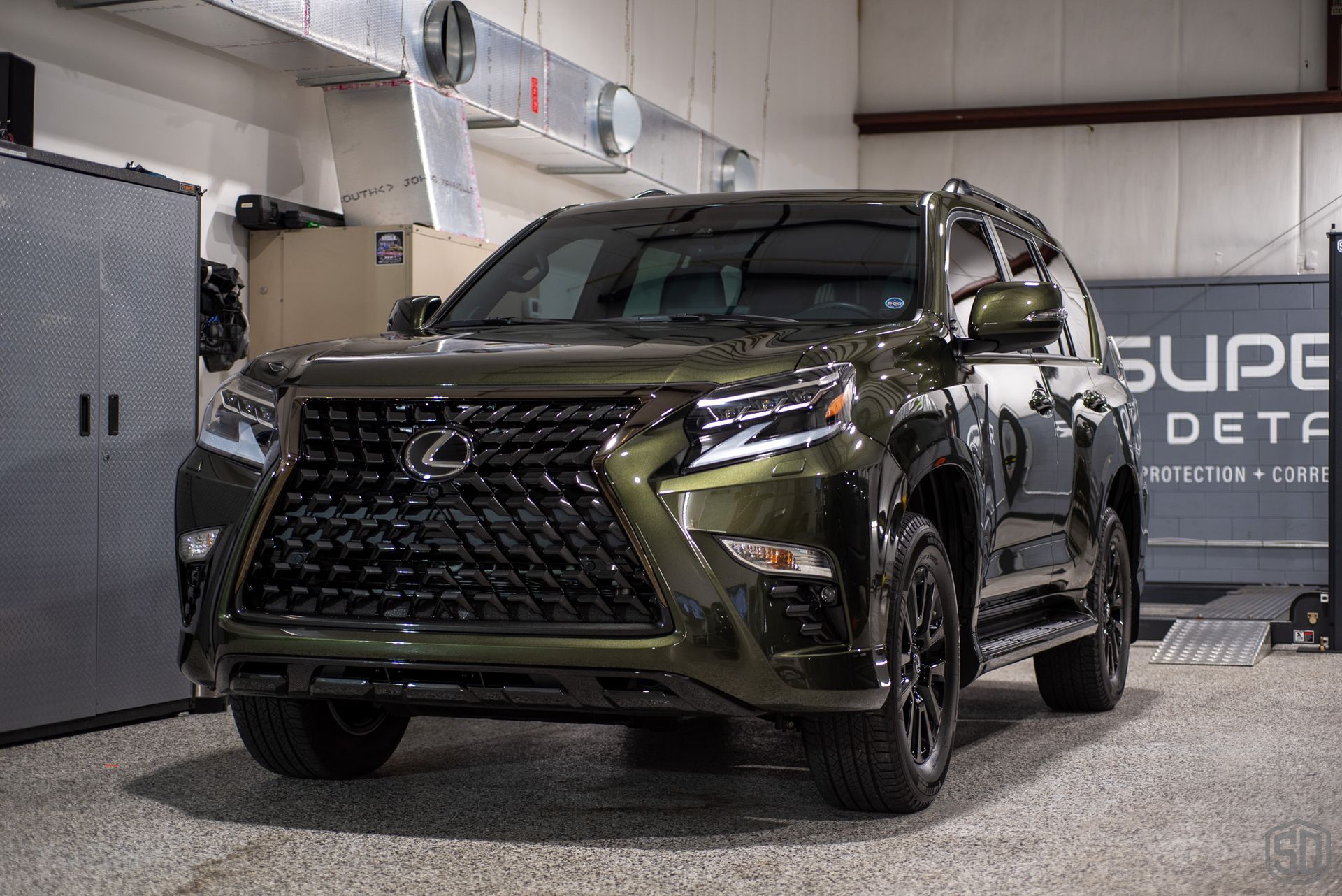 A green lexus suv is parked in a garage.