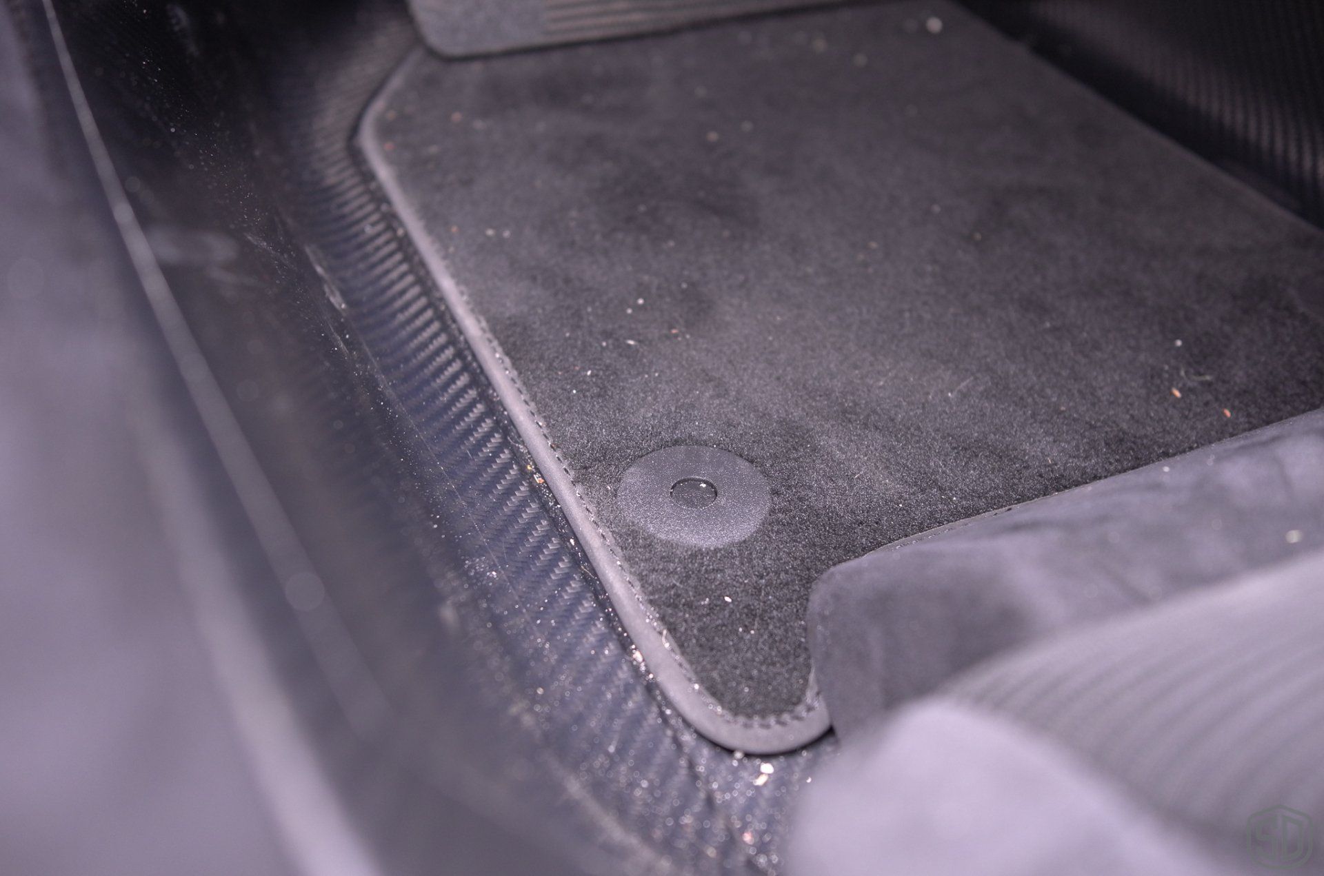 A close up of a dirty floor mat in a car.