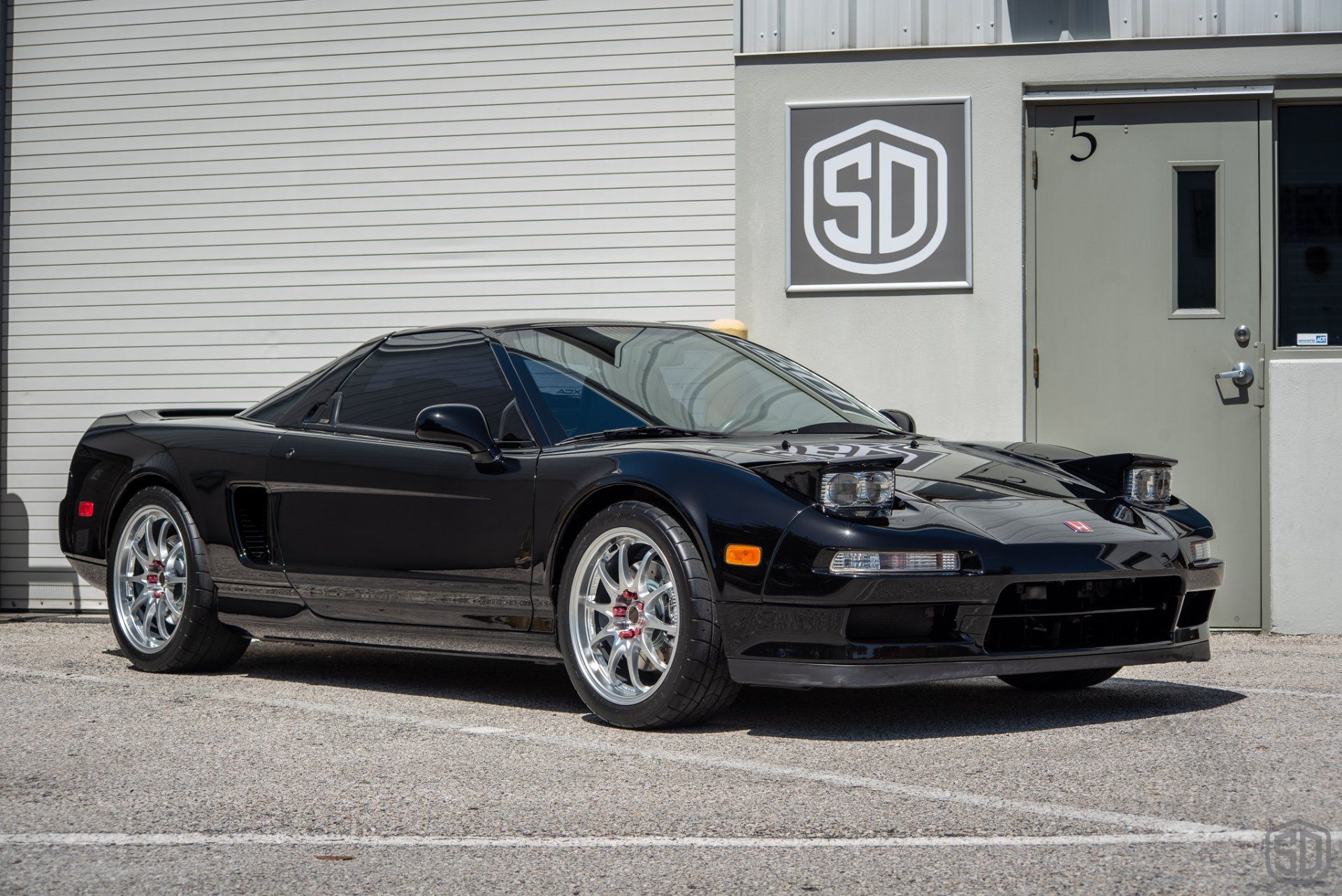 A black sports car is parked in front of a building.