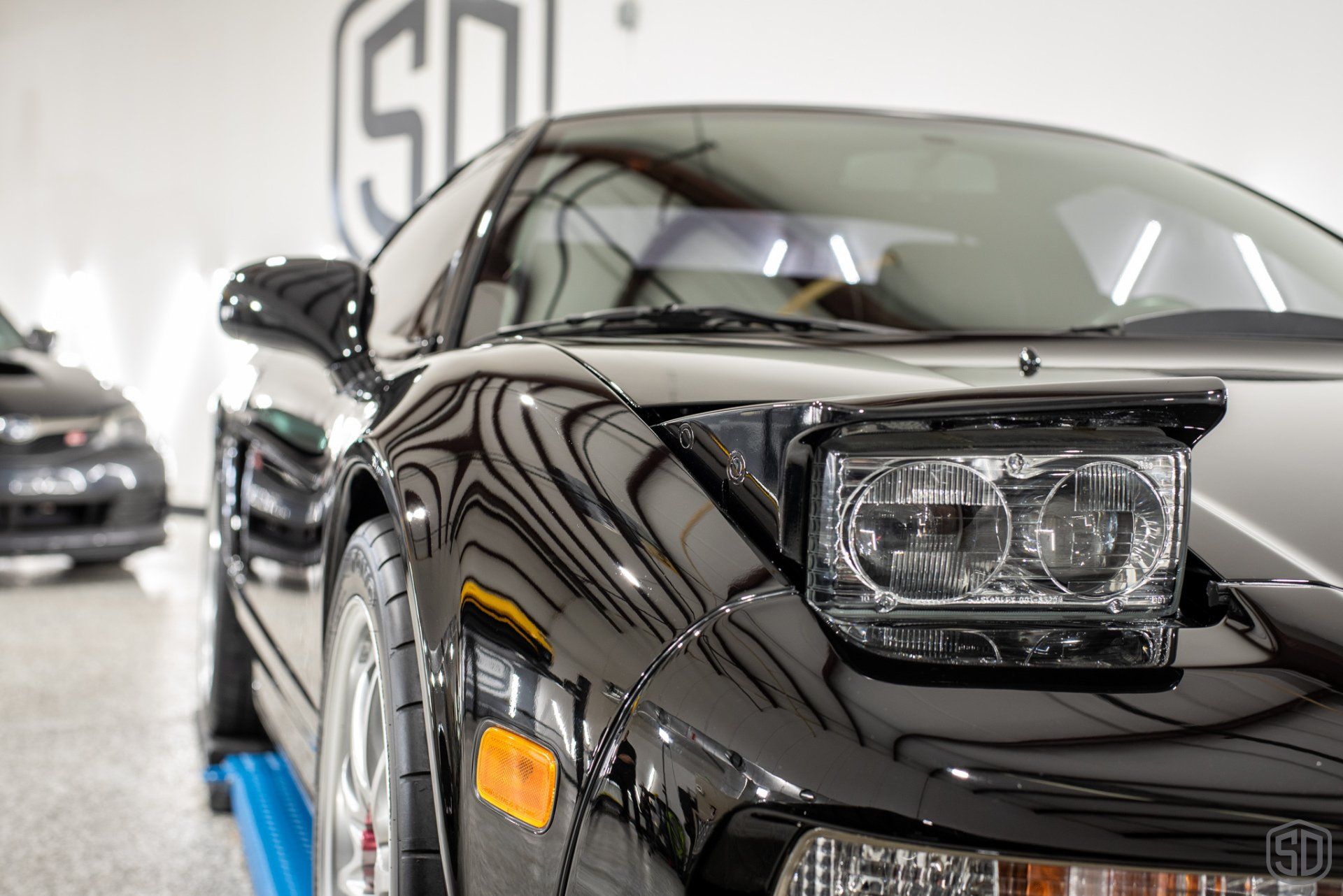 A close up of a black sports car parked in a garage.