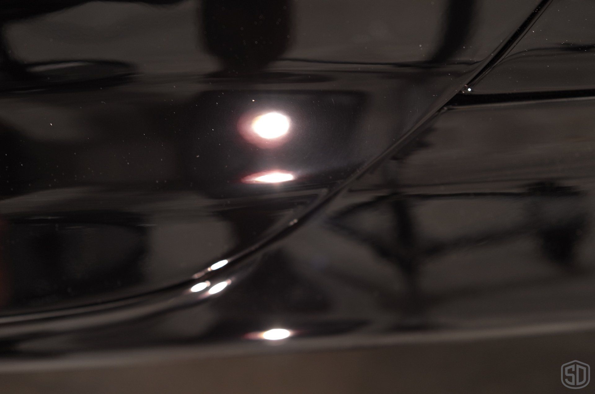 A close up of a black car with a light shining on it.