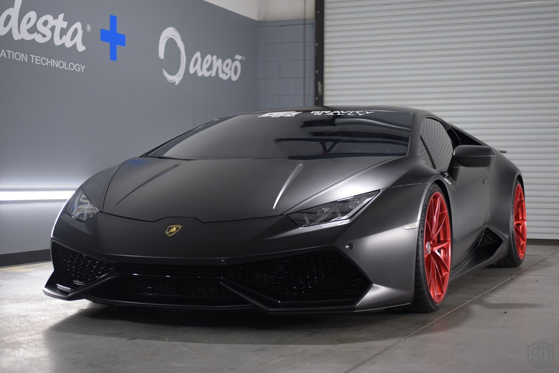 A black lamborghini with red wheels parked in a garage.