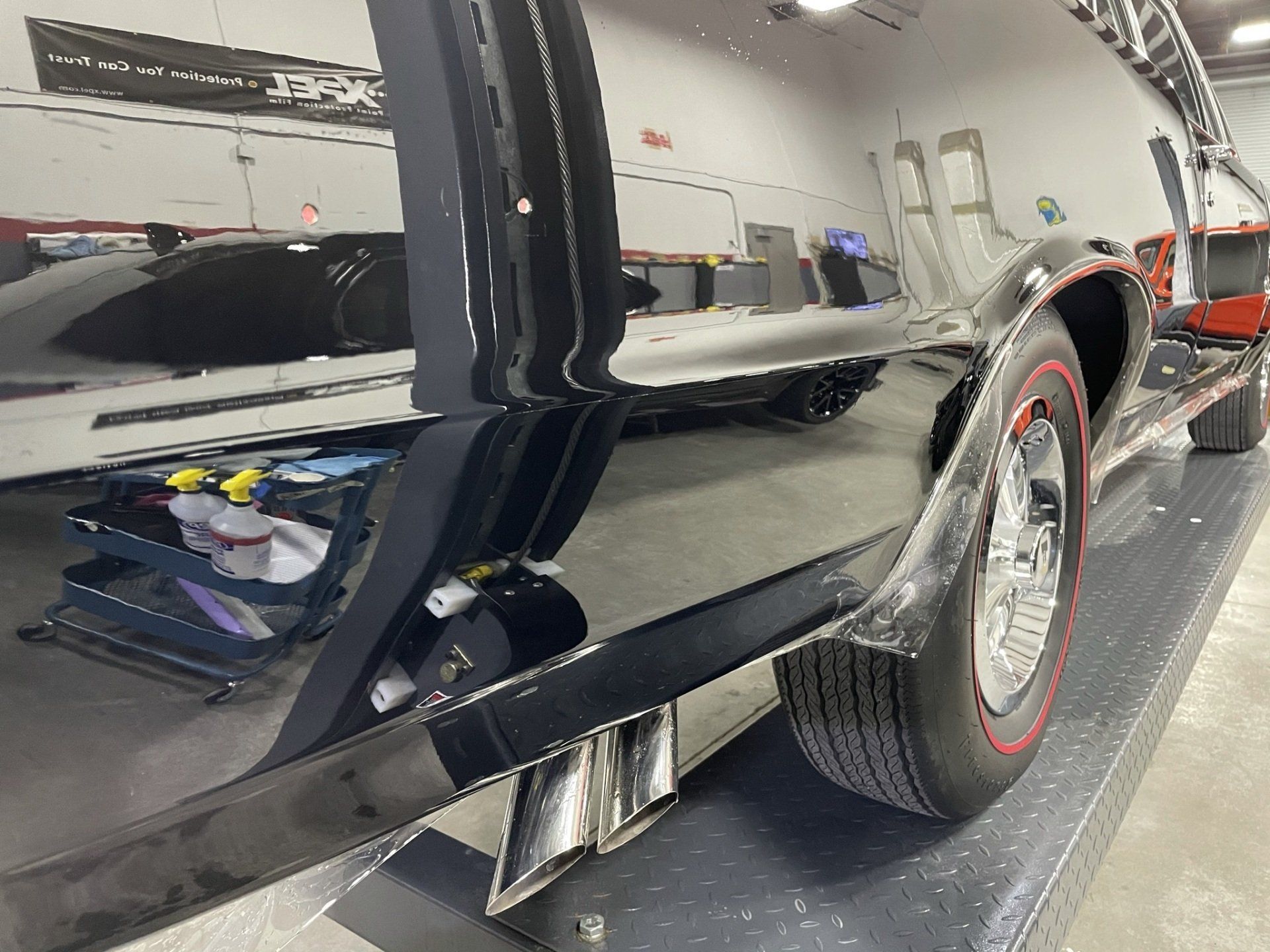 A black car is parked in a garage on display.