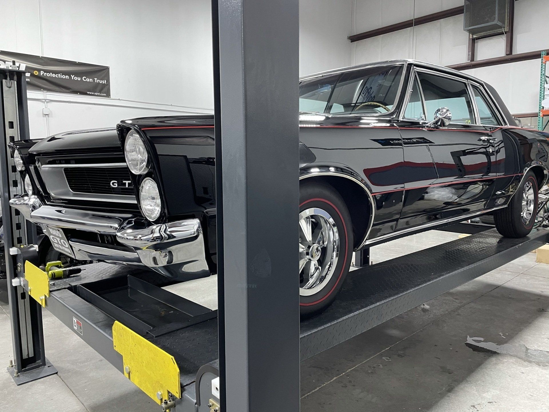 A black car is parked on a lift in a garage.