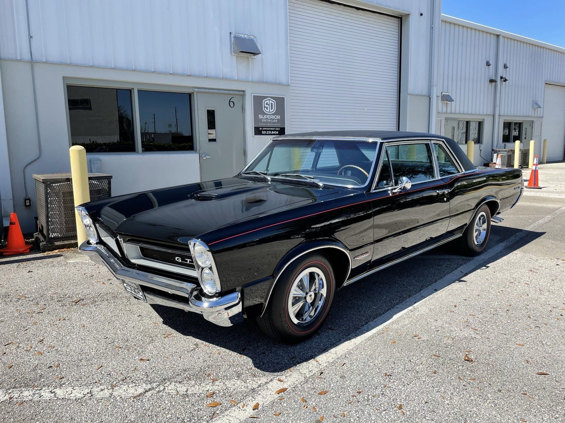 A black car is parked in a parking lot in front of a building.