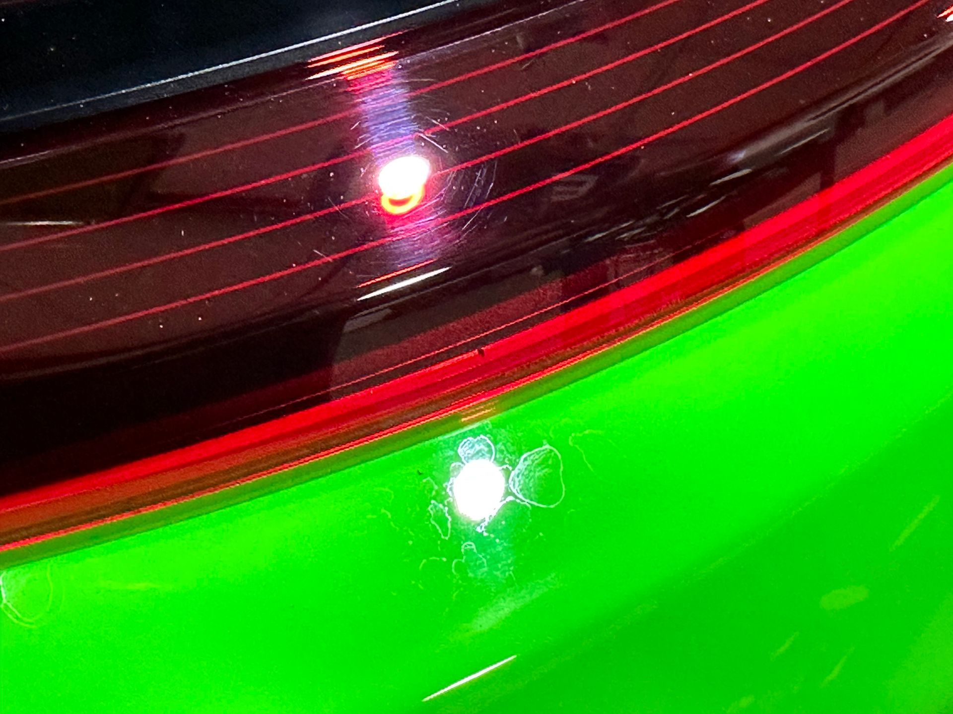 A close up of a green car with a red tail light.