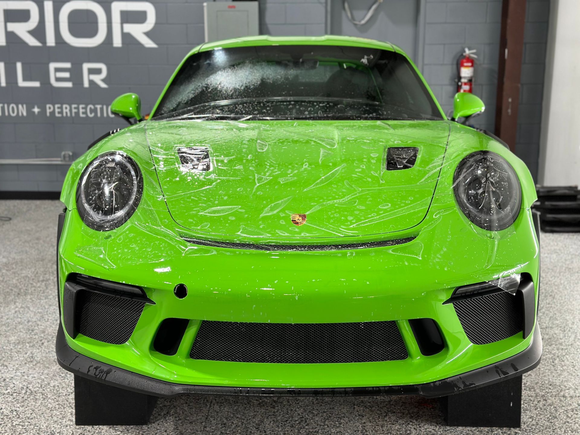 A green porsche 911 gt3 rs is parked in a garage.