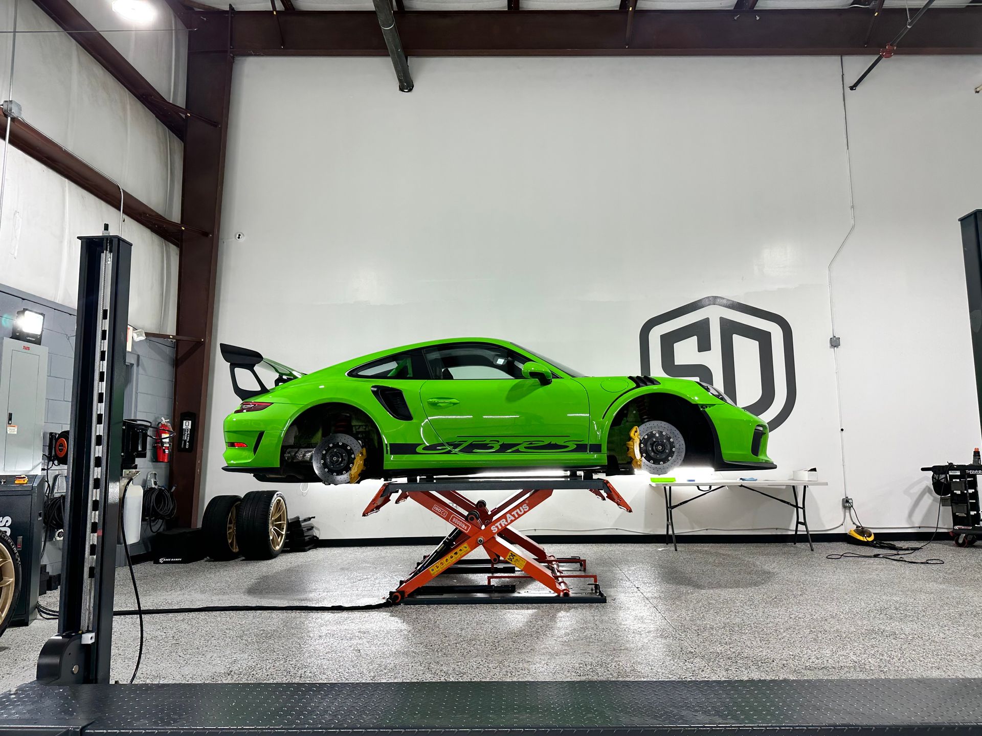 A green sports car is parked on a lift in a garage.