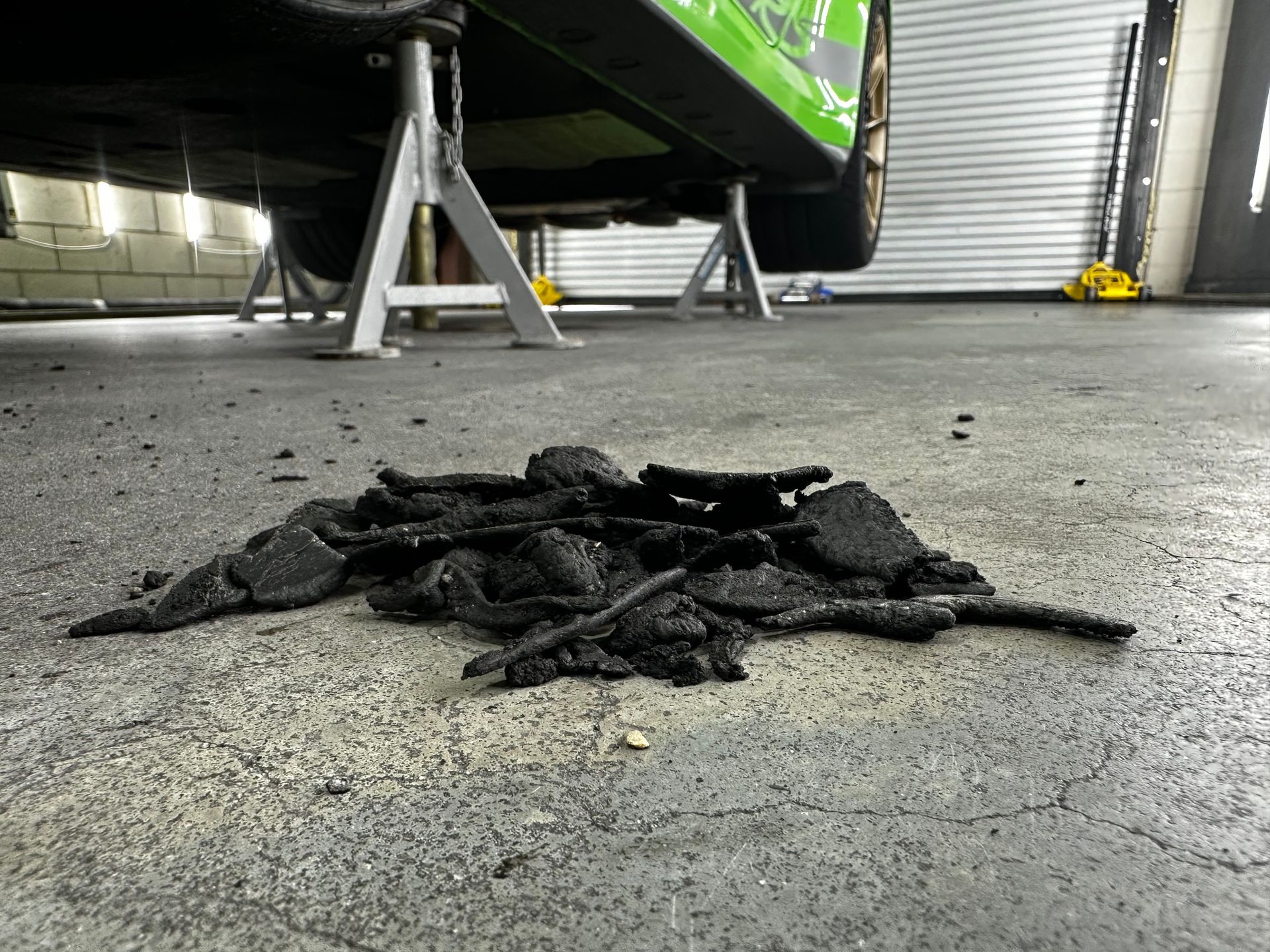 A pile of coal is laying on the ground under a car