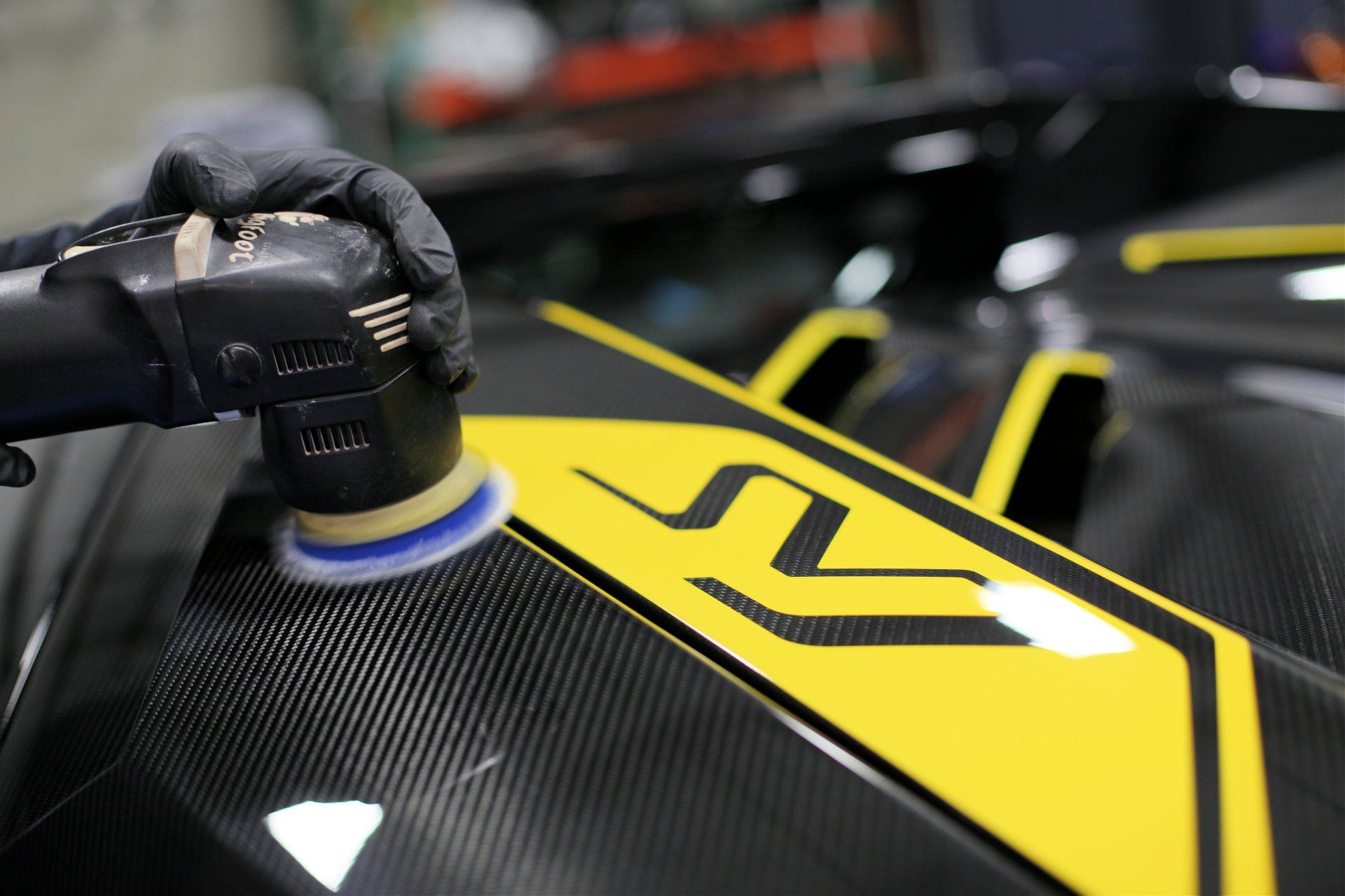 A person is polishing a car with a machine.