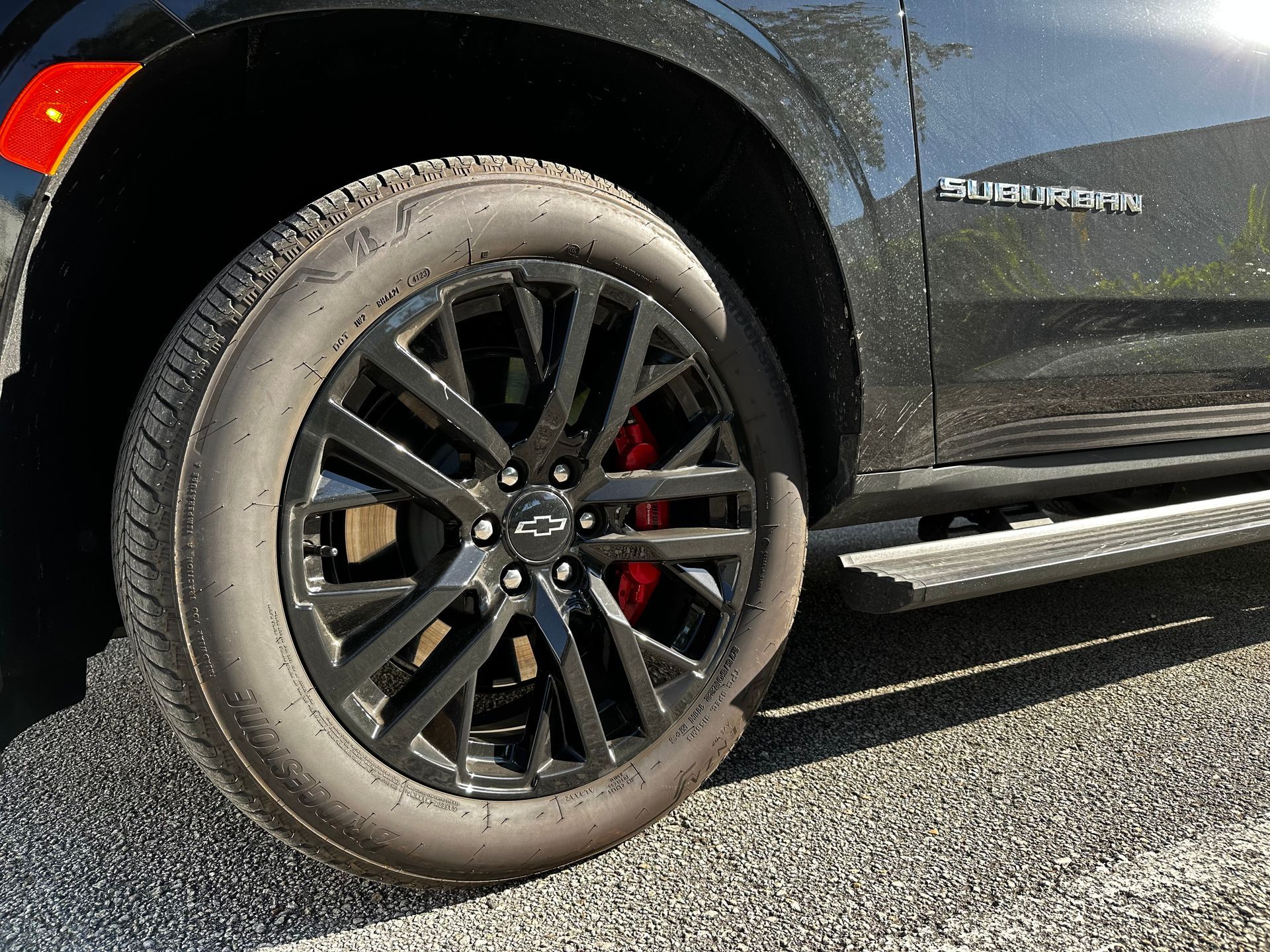 A black suv with red brake calipers is parked on the side of the road.