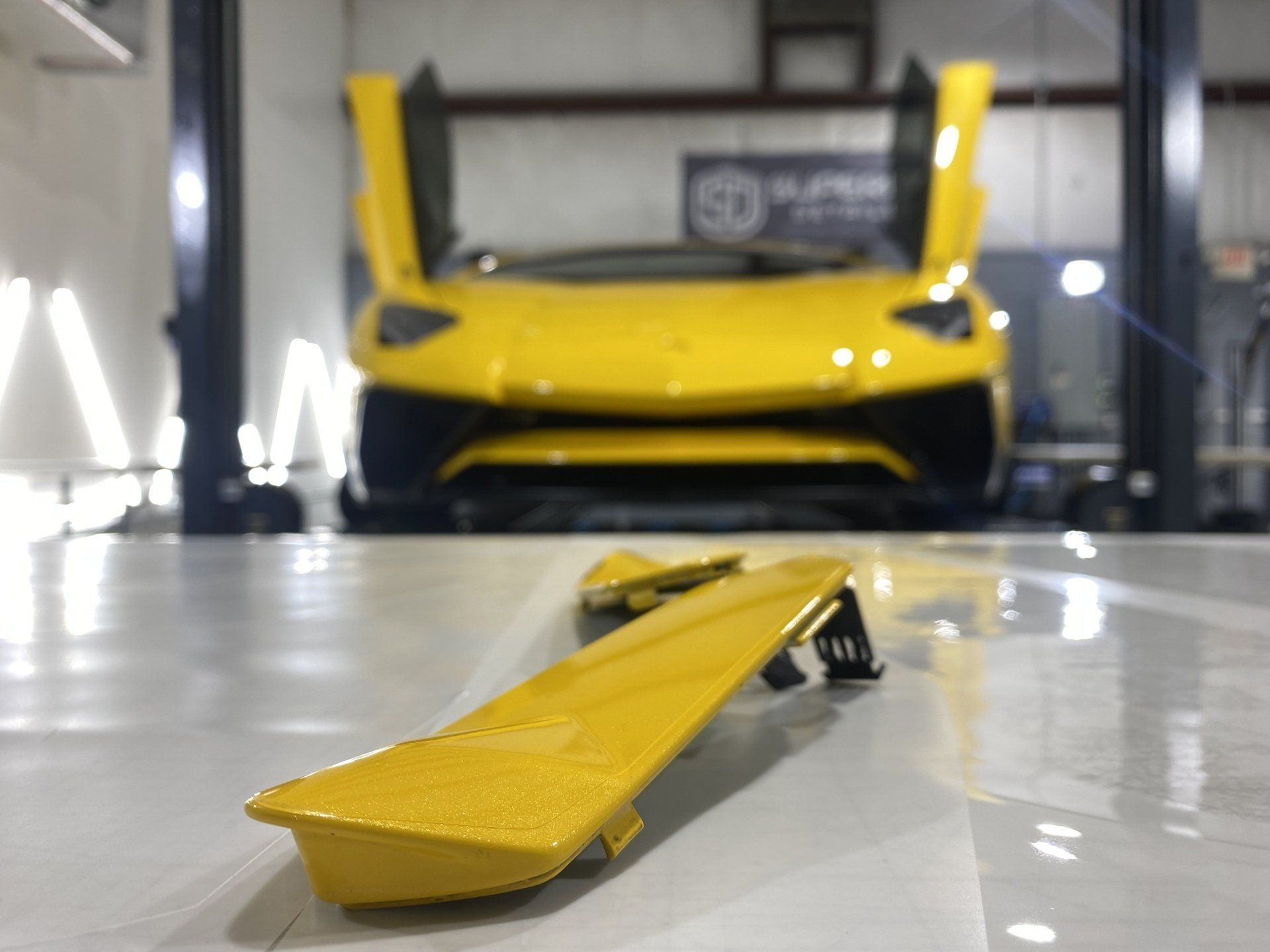 A yellow lamborghini is parked in a garage with its doors open