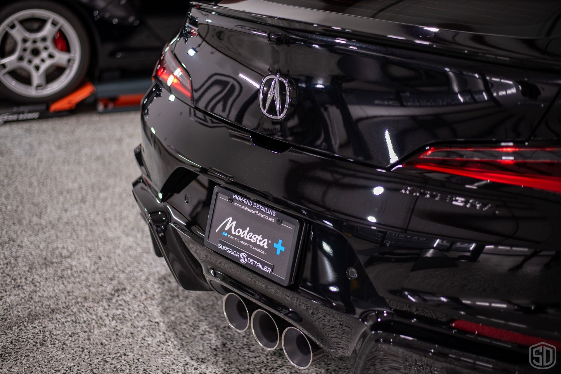 A blue car with a red tail light is parked in a garage.