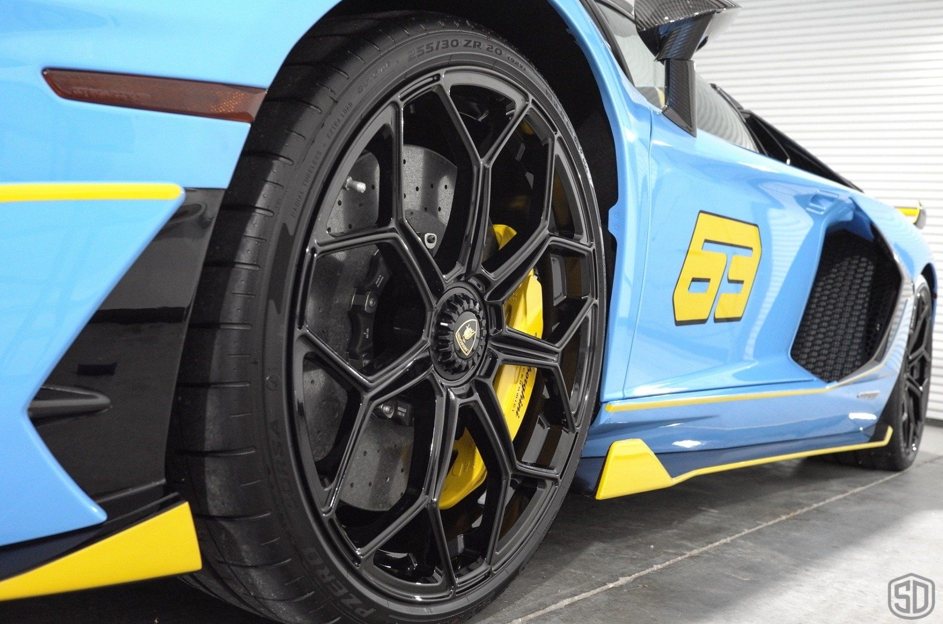 A blue and yellow sports car with the number 69 on the side is parked in a garage.