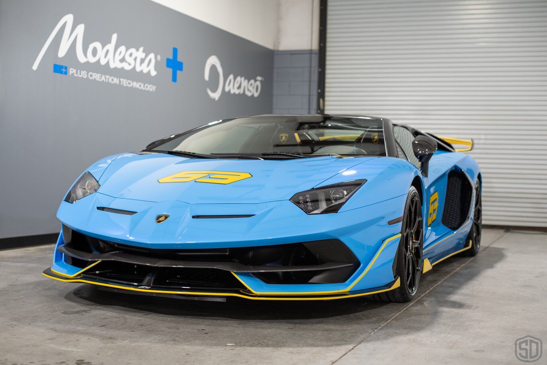 A blue lamborghini aventador is parked in a garage.