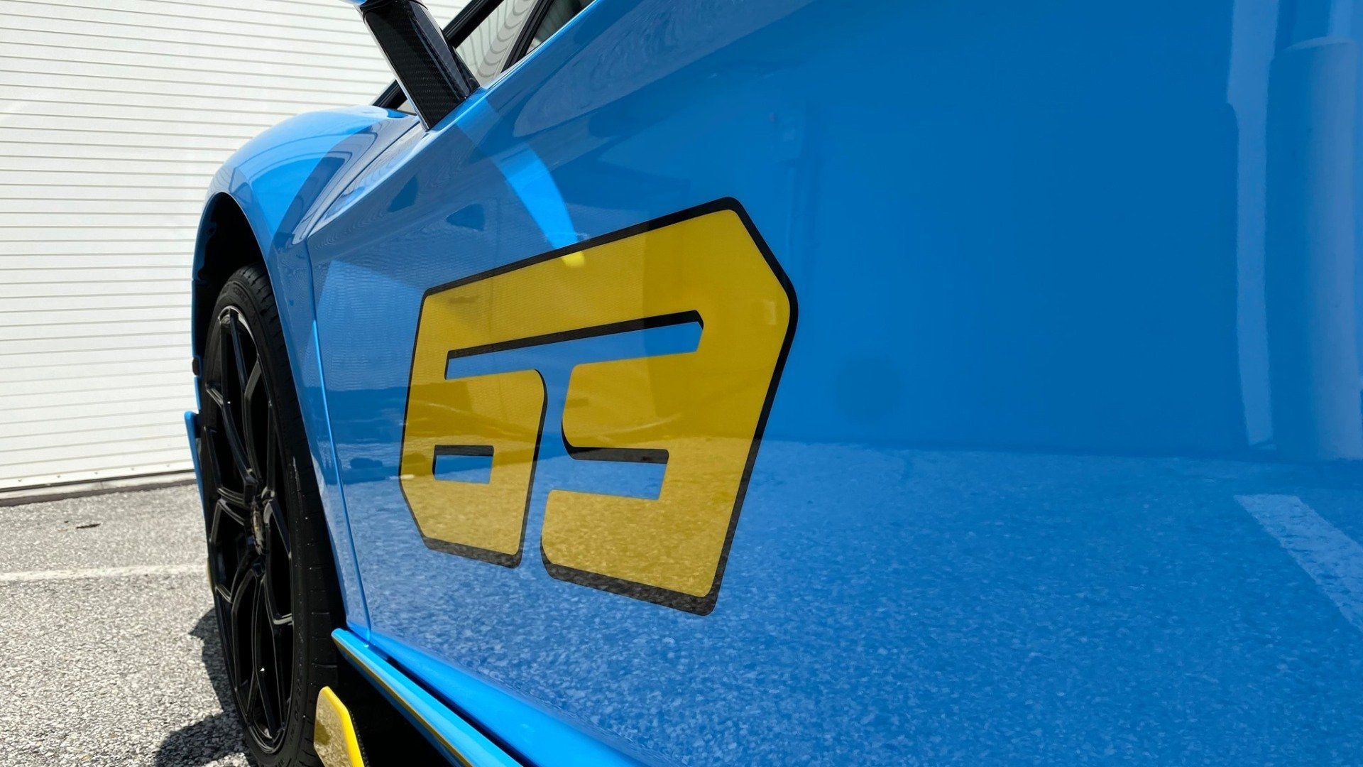A close up of a blue car with a yellow sticker on the side.