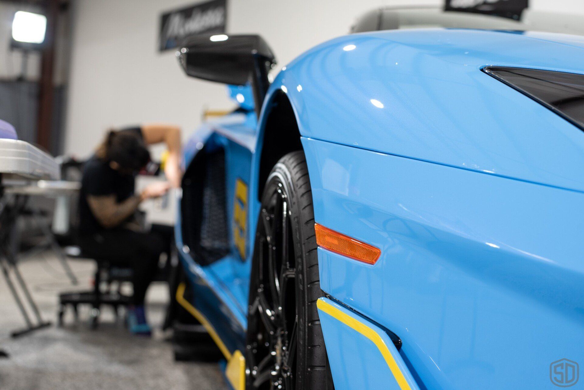 A blue lamborghini aventador is parked in a garage.